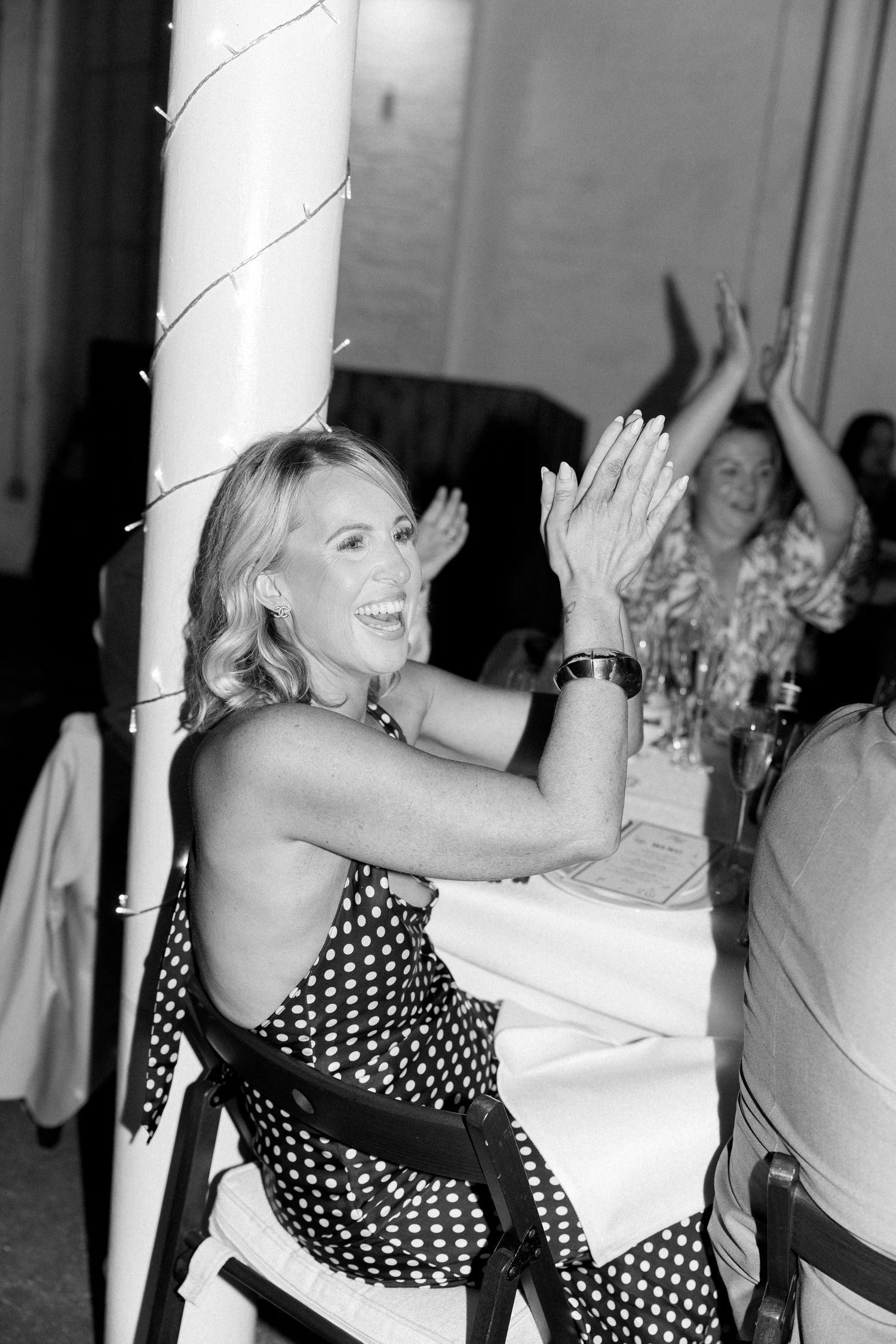 Wedding guests dancing and celebrating in polka dot dress near white pillars.