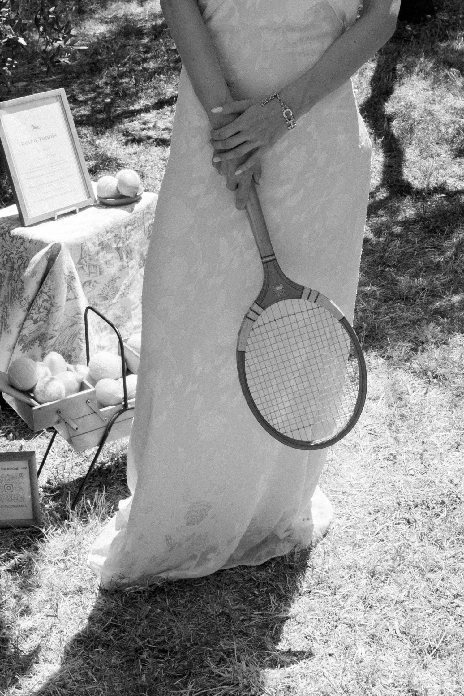Black and white photo of tennis rackets and equipment laid out on grass in bright sunlight.