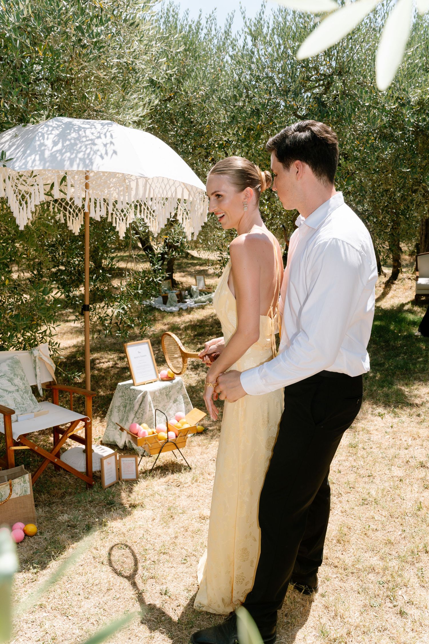 A couple shares an intimate moment under a parasol in an olive grove during their wedding.