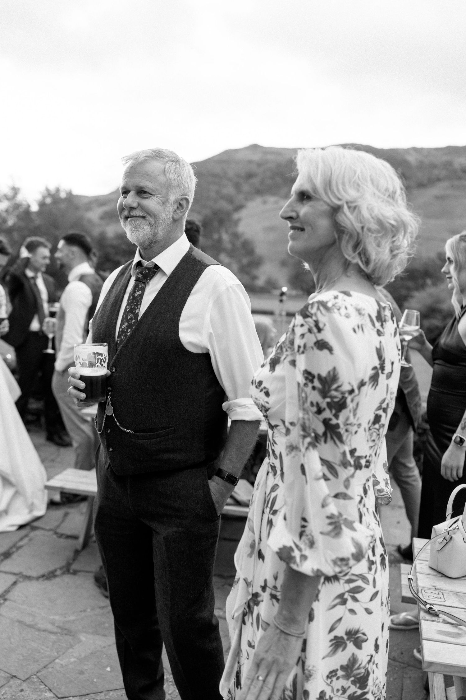 Wedding guests mingling at outdoor reception with mountain backdrop.