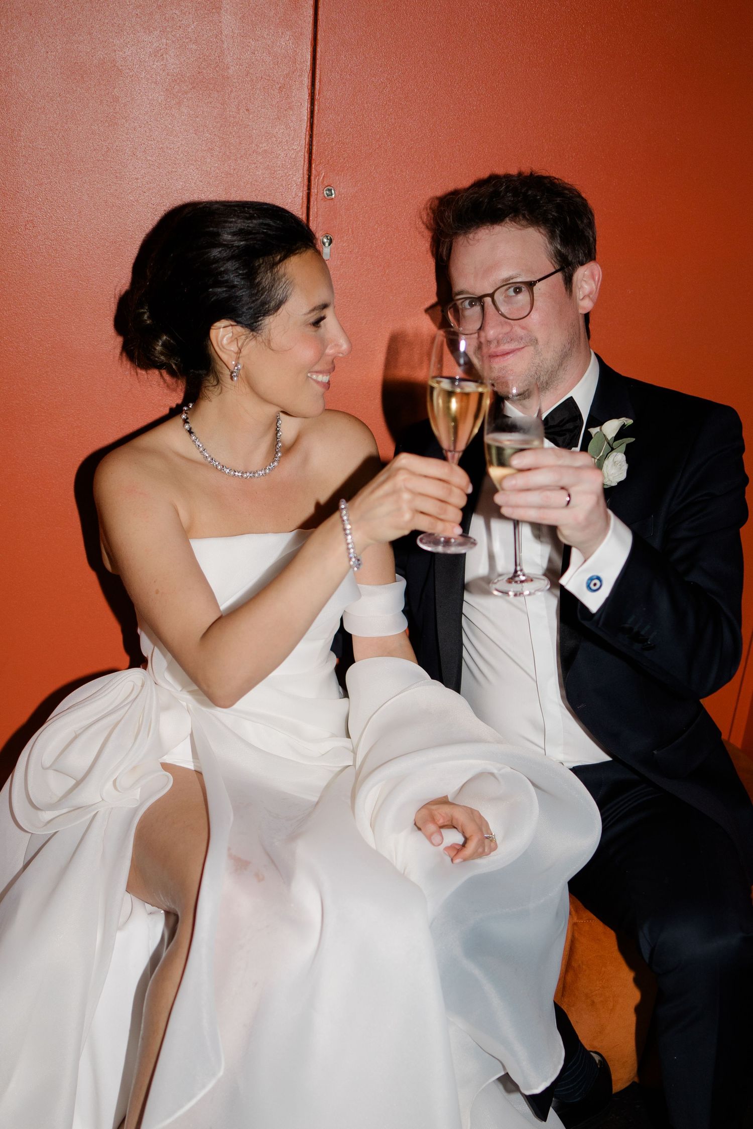 A couple toasts with champagne glasses while sharing an intimate moment at their wedding reception.