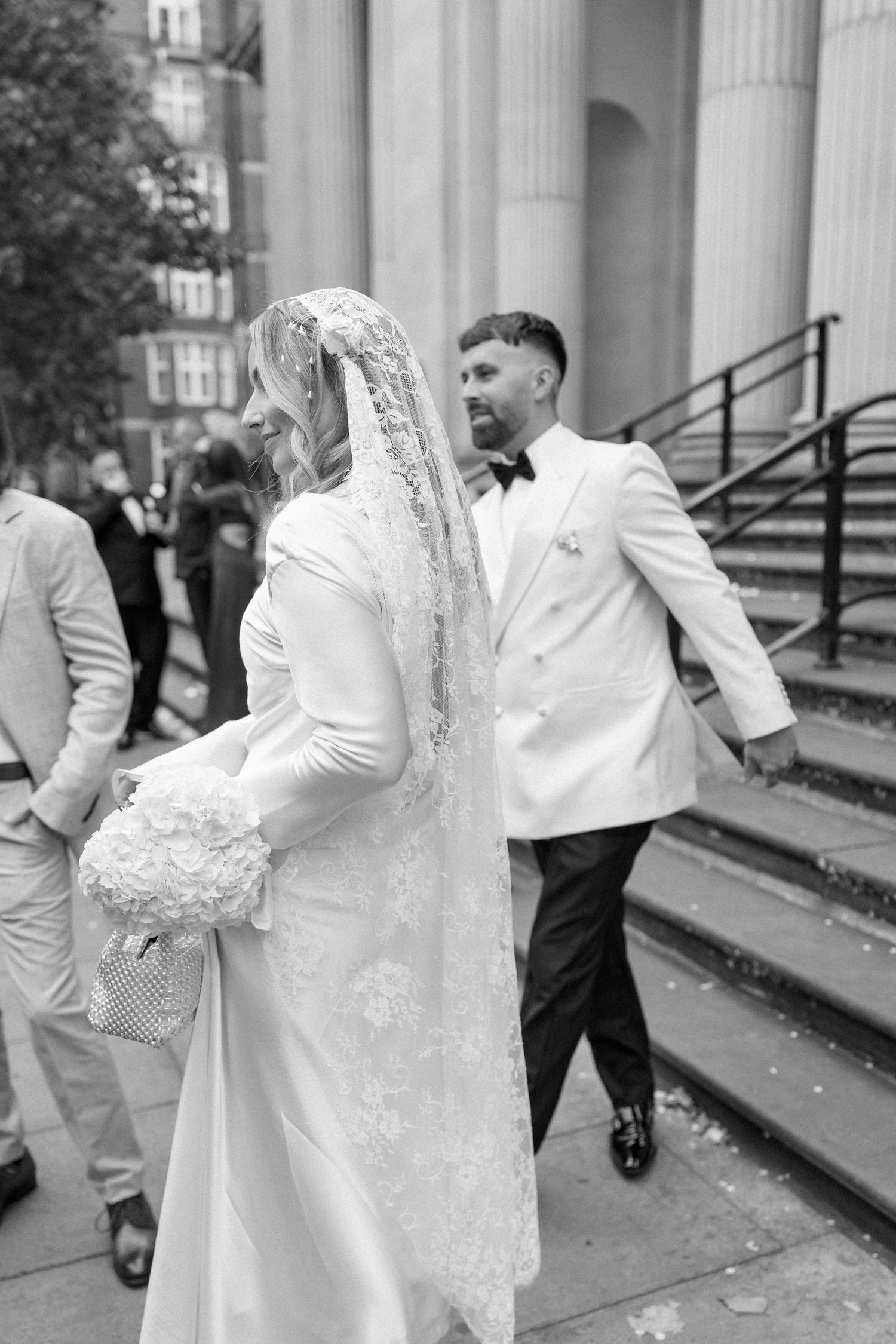 Black and white photo of couple on stone steps with architectural columns in background.