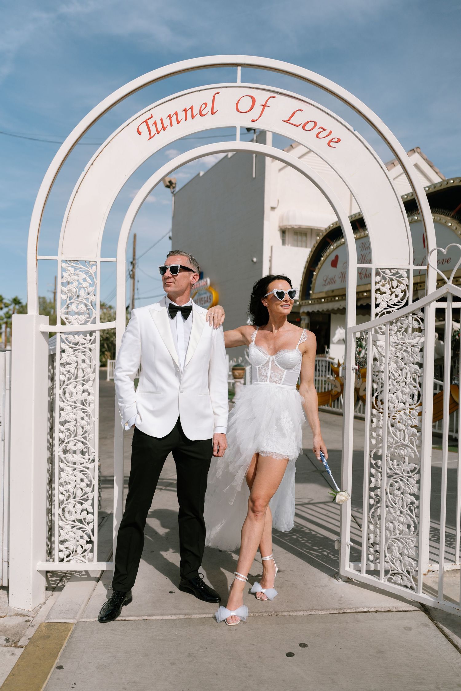 A couple walks through an ornate white archway labeled 'Tunnel of Love' in Las Vegas.