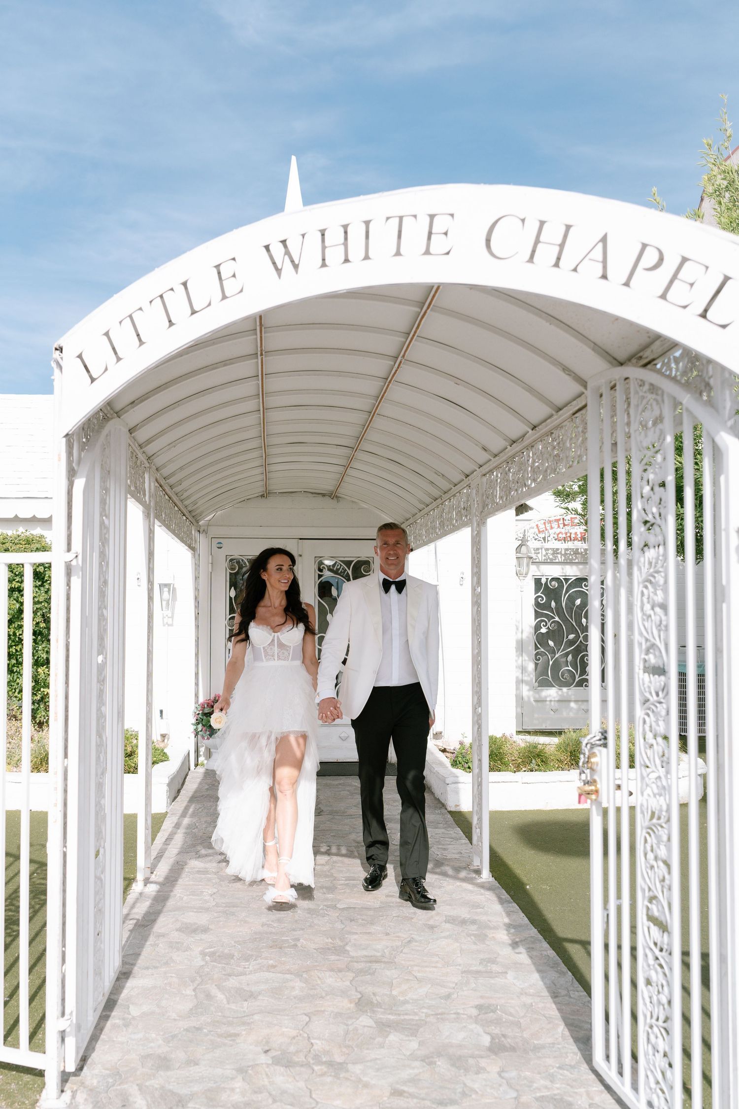 Elegant white chapel walkway with arched columns and wedding couple.
