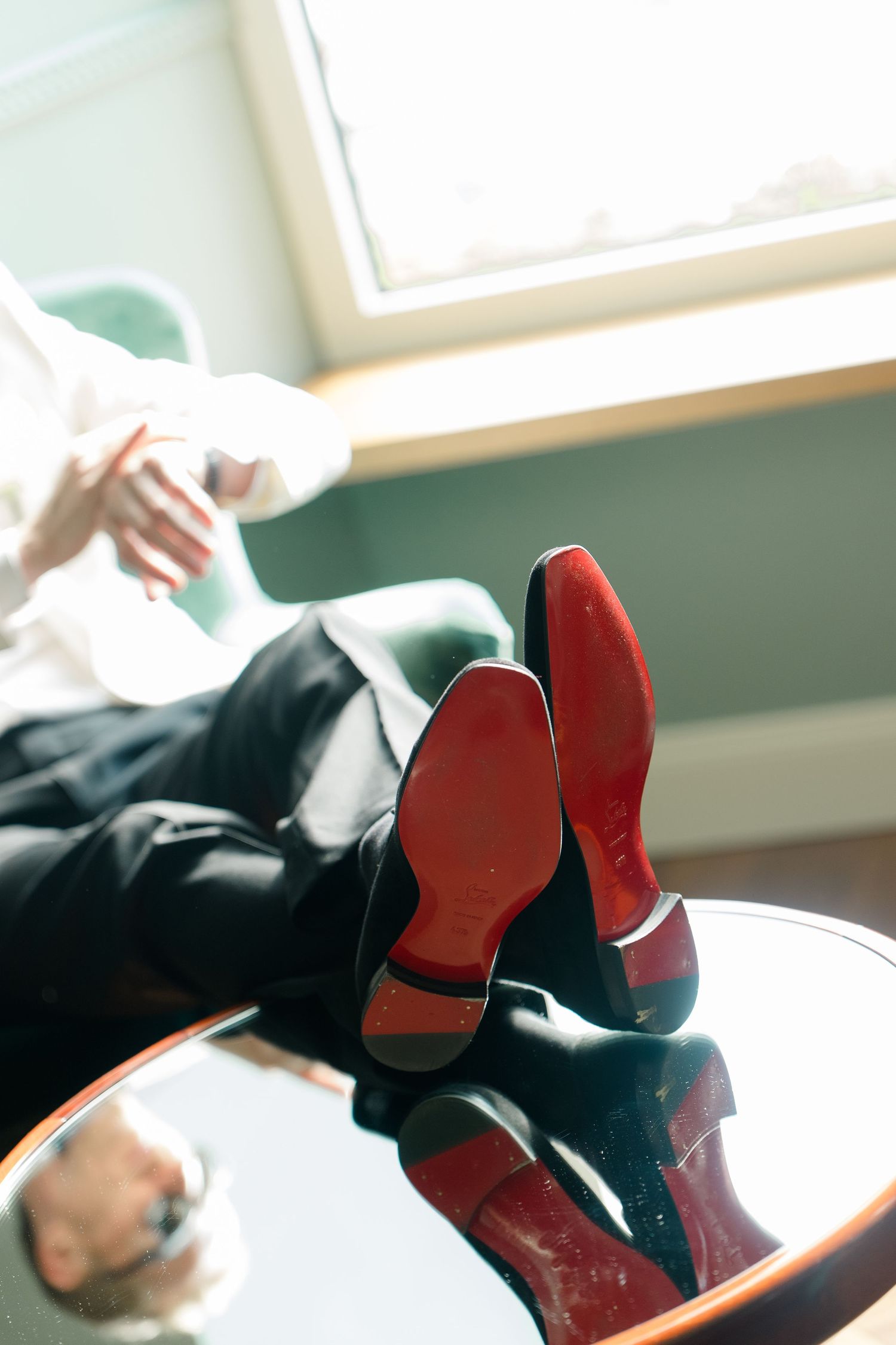 Close-up of red-soled Louboutin heels resting on a glass table in a luxury hotel room.
