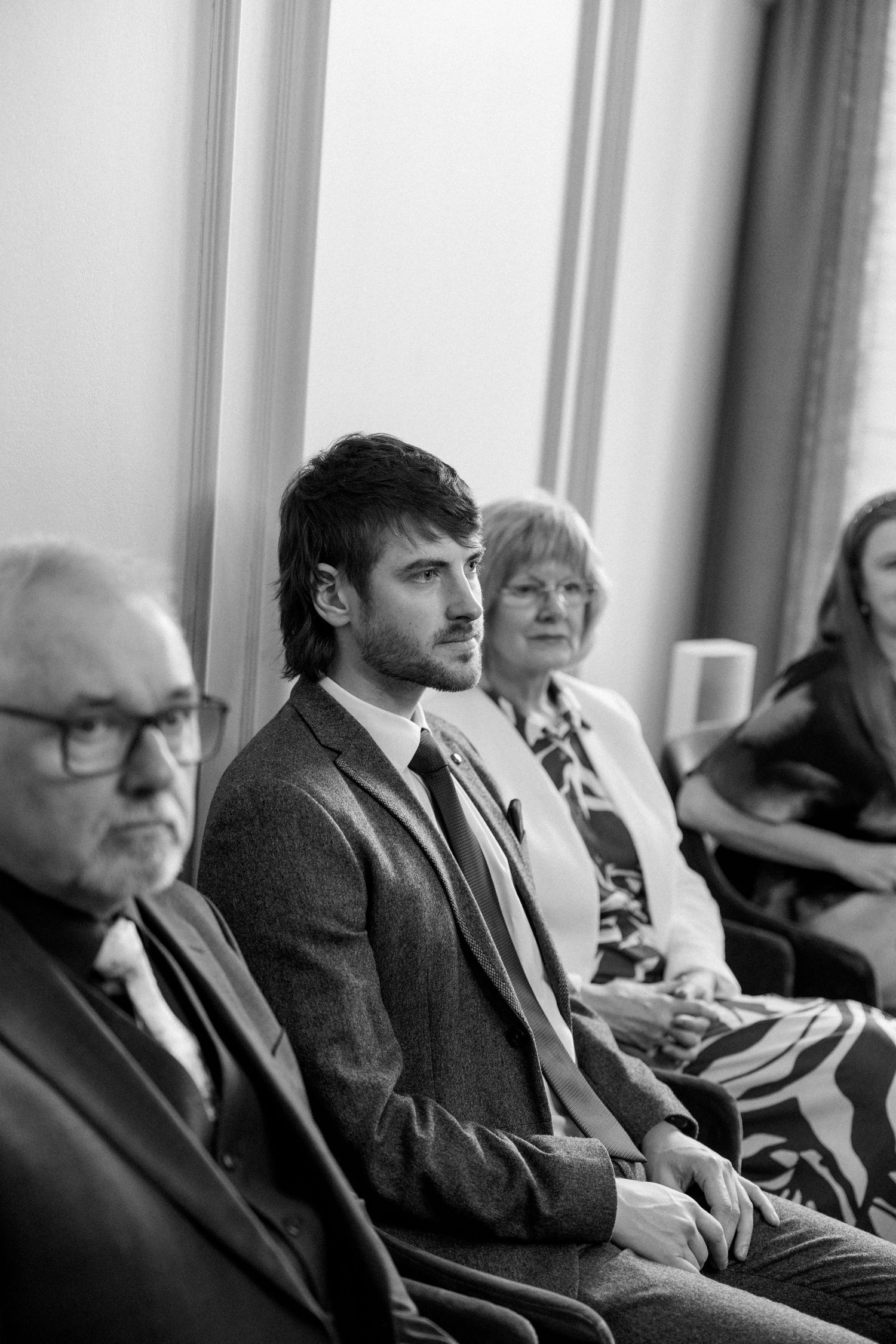Wedding guests seated in a row during an indoor ceremony.