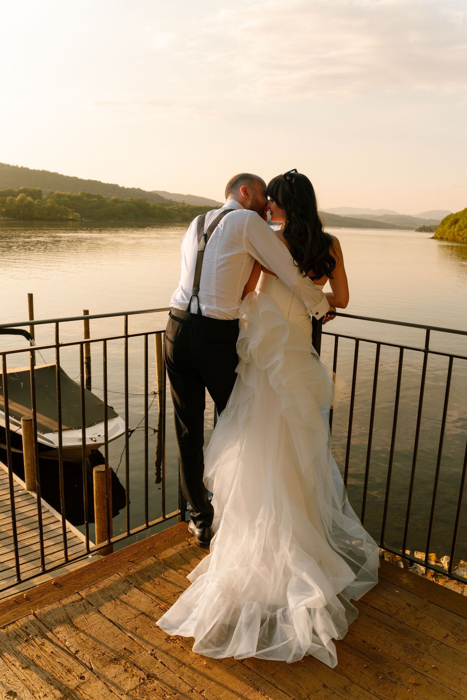 A romantic moment on a wooden deck overlooking a serene lake at sunset.