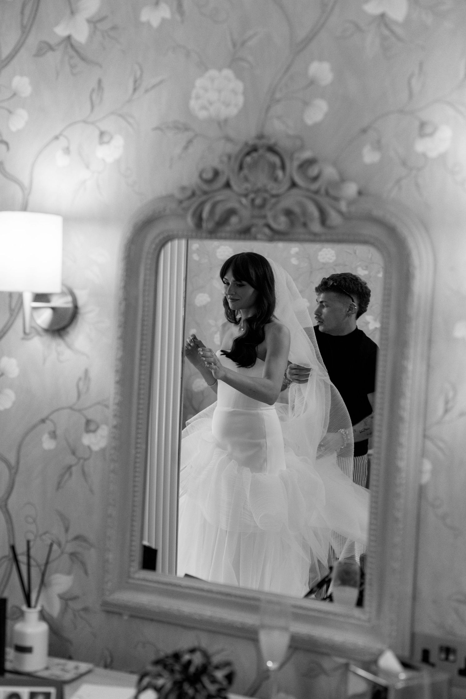 Black and white photos showing reflections in an ornate mirror with floral wallpaper background.