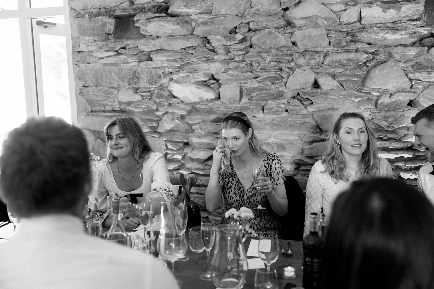 Candid moments of wedding guests dining at an elegant reception in a stone-walled venue.