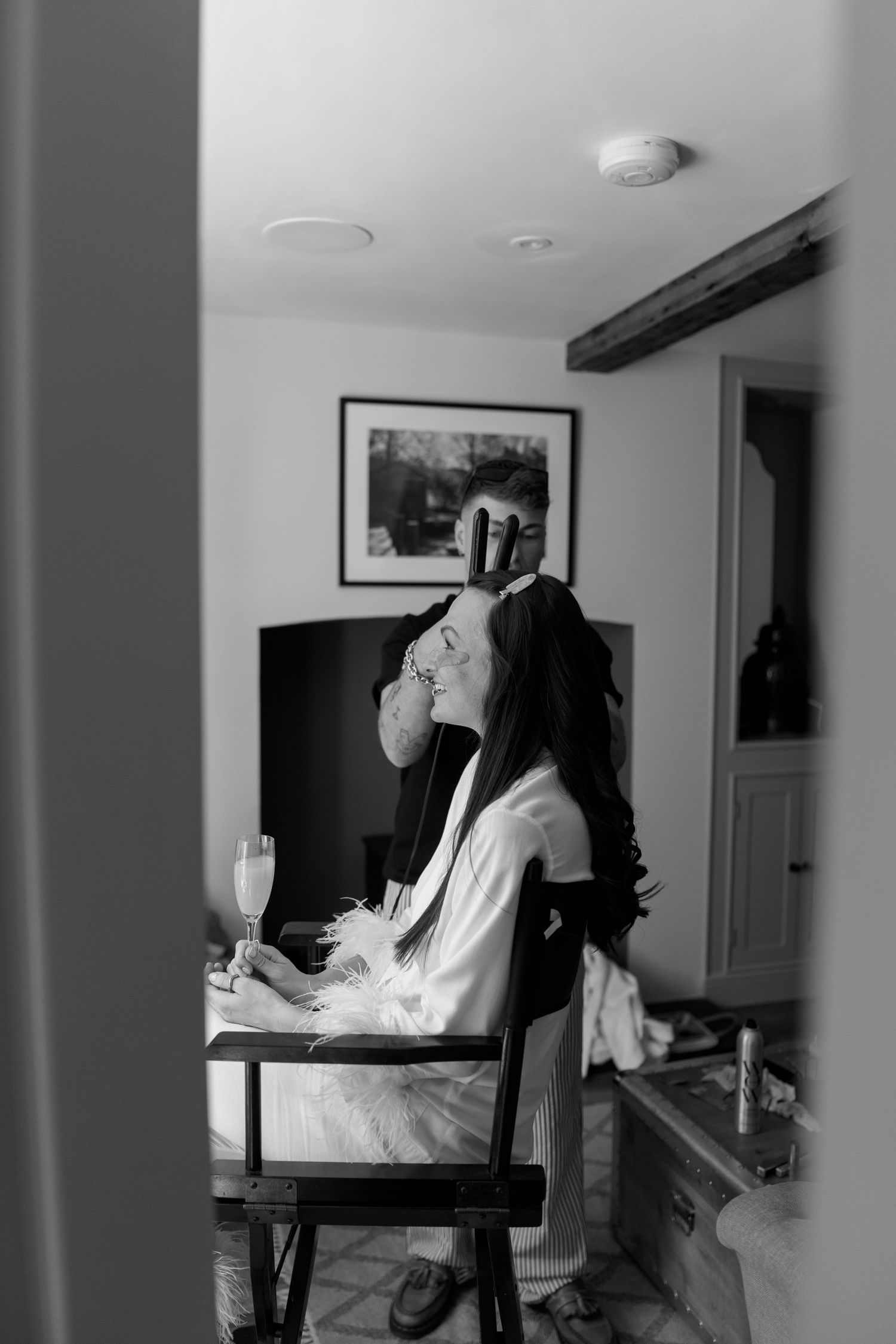 Person in white robe relaxing in chair with champagne glass.