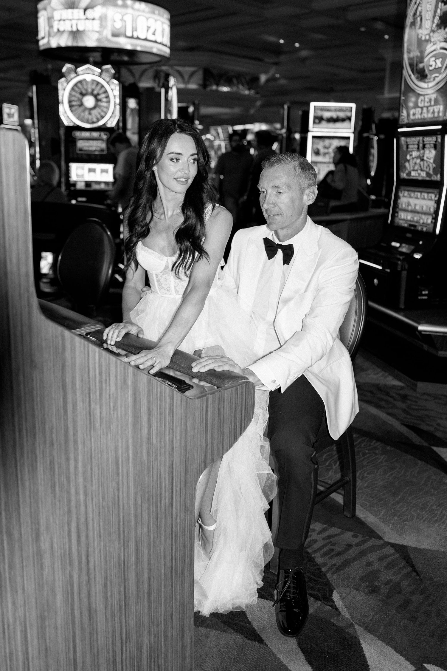 Wedding couple enjoys playful moments at casino gaming tables.