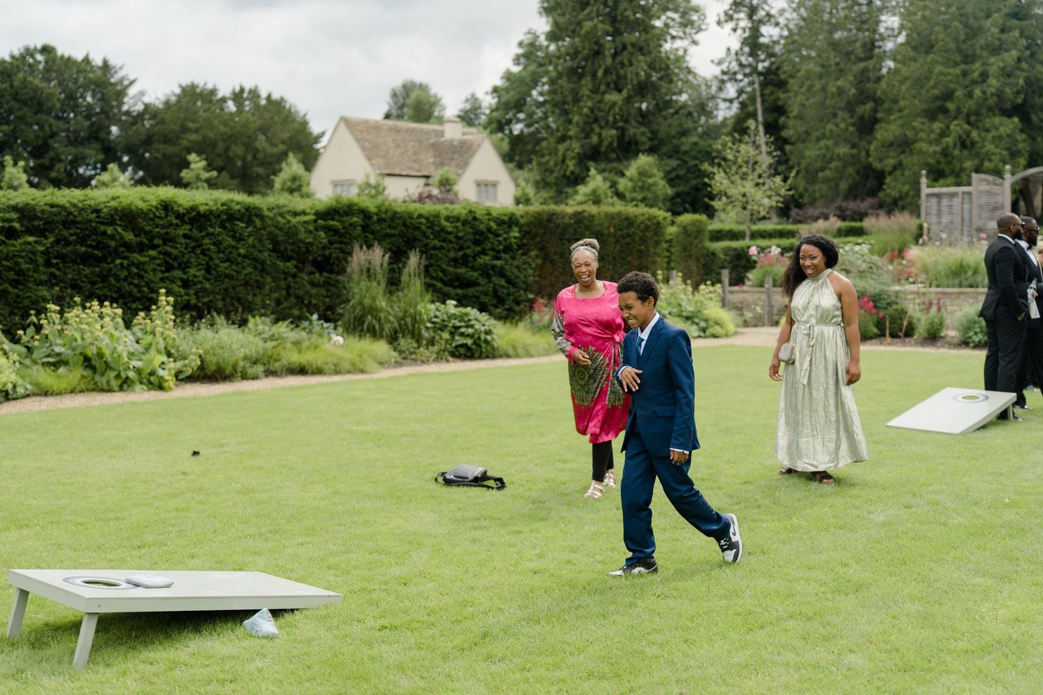 Wedding guests playing cornhole lawn game in a beautiful garden during a reception.