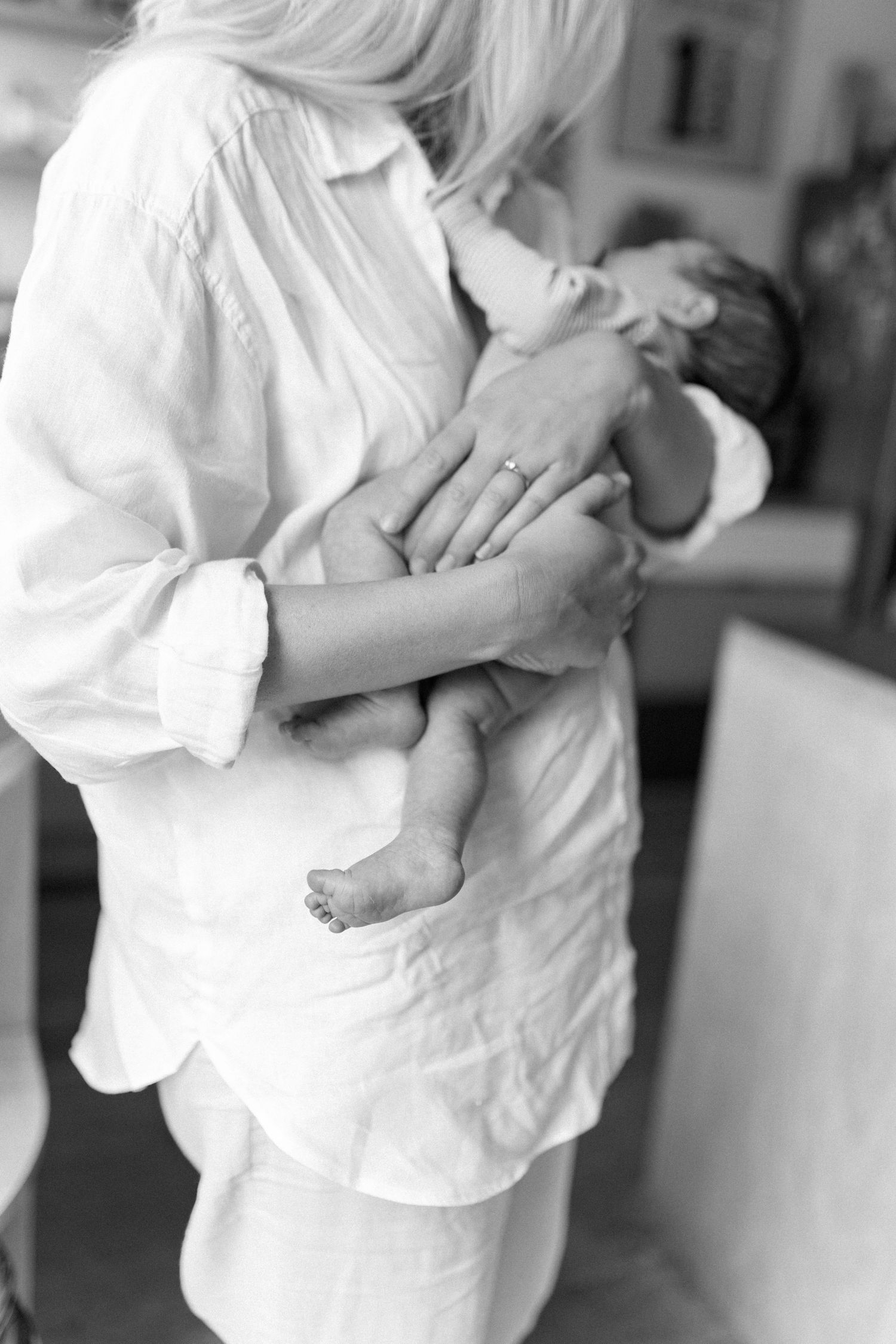 Parent in white shirt embraces and nurtures infant in peaceful black and white photo sequence.