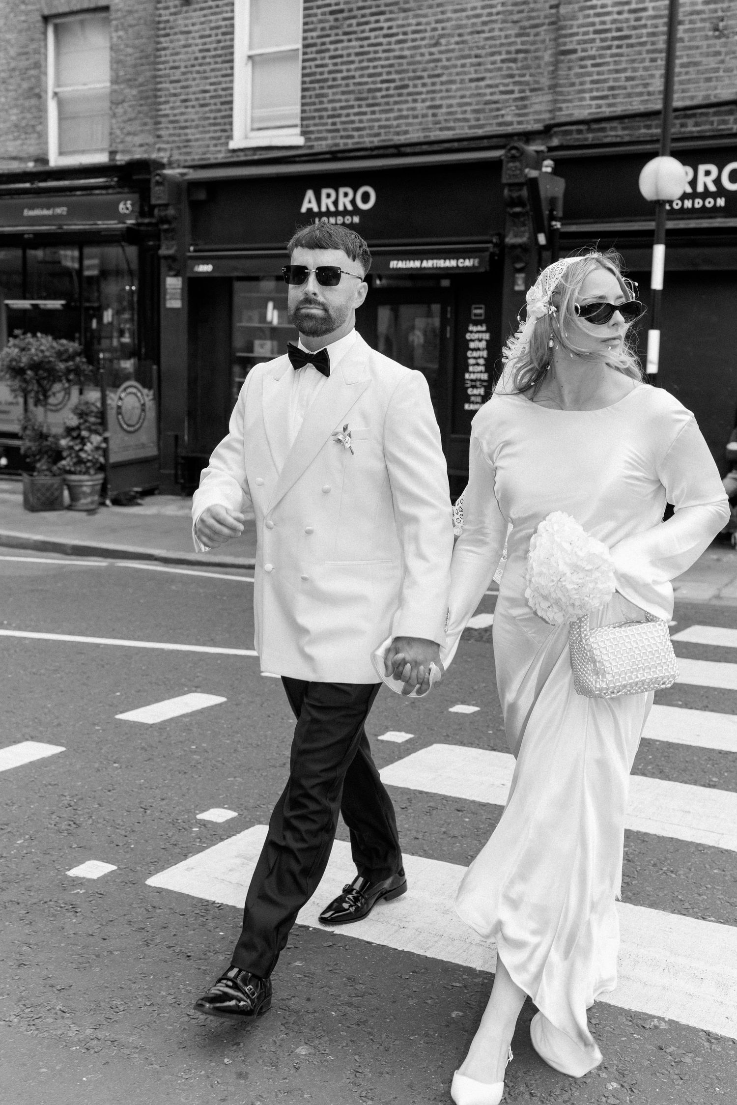 Couple walking across a crosswalk in formal wedding attire in black and white.