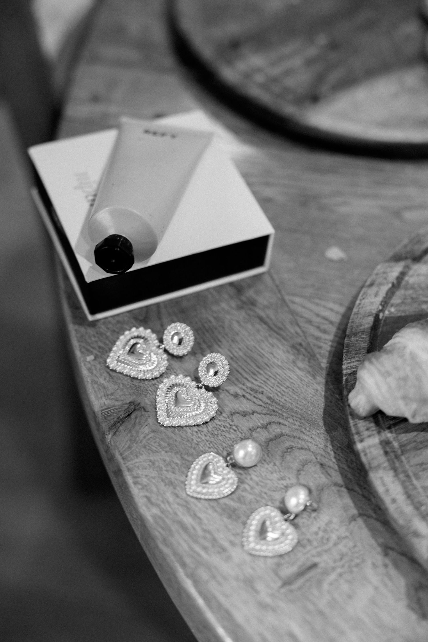 Pearl and crystal heart-shaped earrings displayed on a rustic wooden surface.