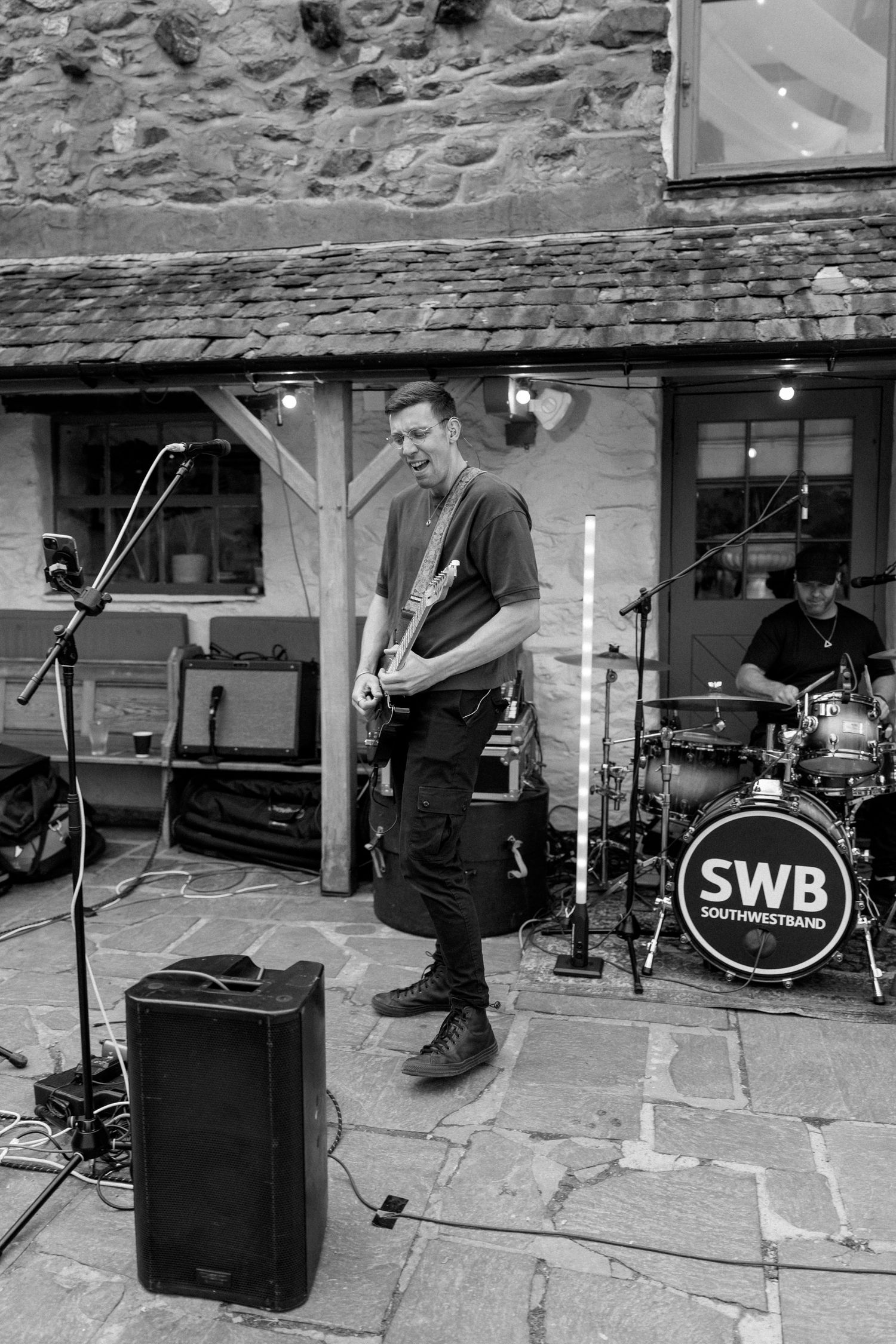 Black and white photo of band setup with instruments and equipment at outdoor venue.
