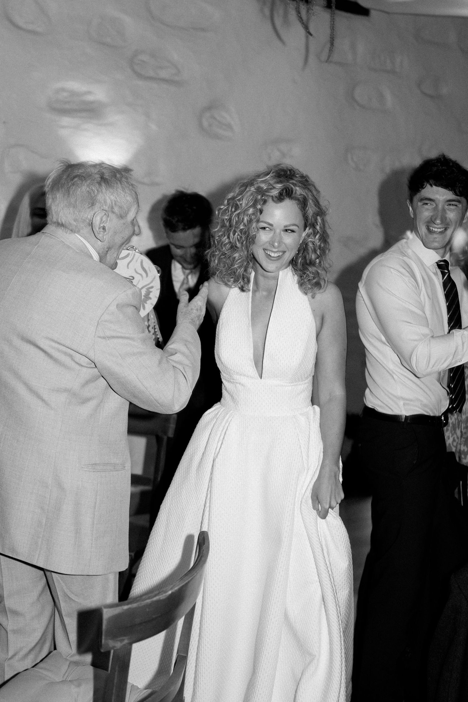 A group of wedding guests dancing and celebrating at an indoor reception.