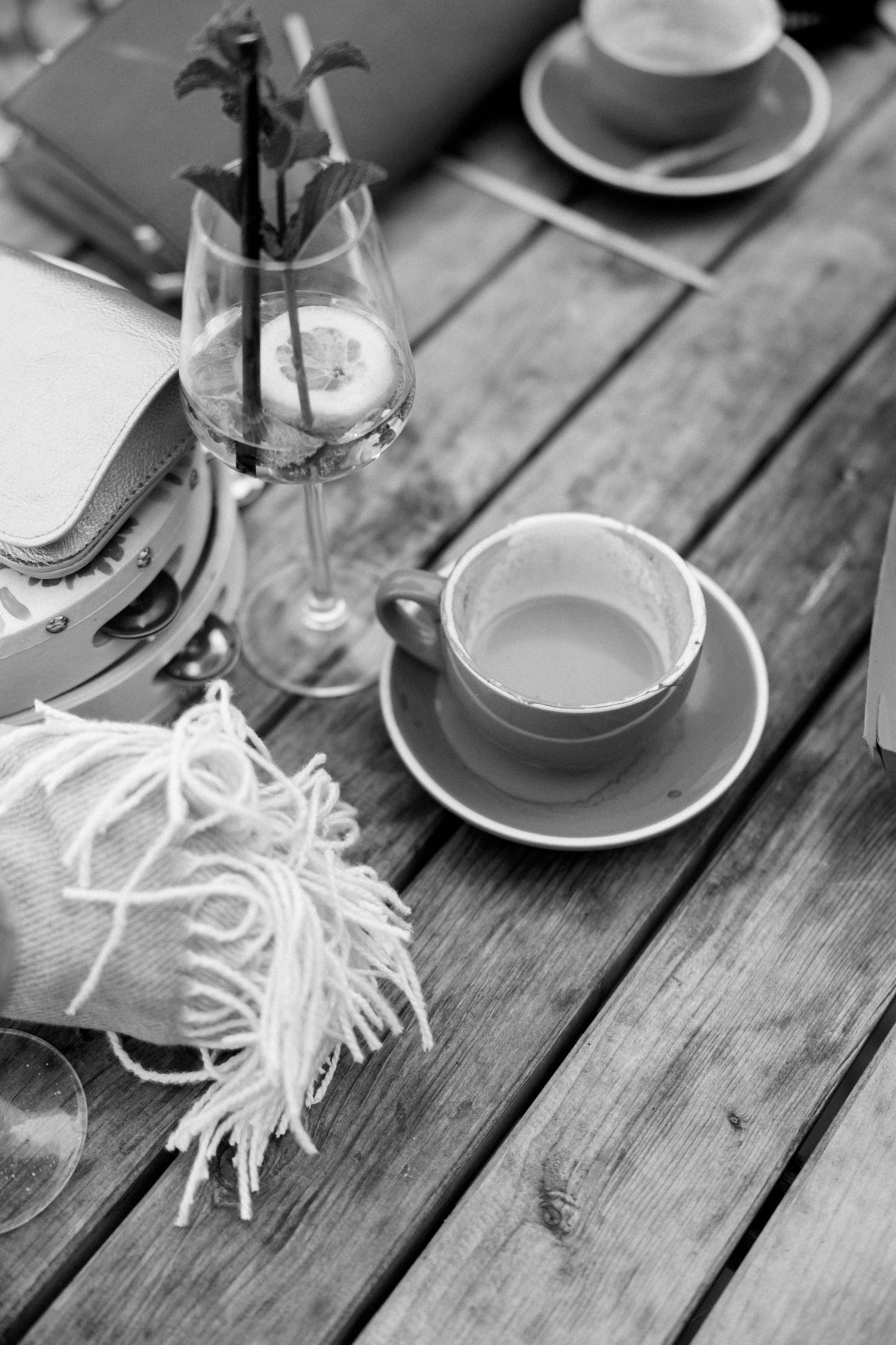 Black and white detail shot of teacups and place settings on wooden table.