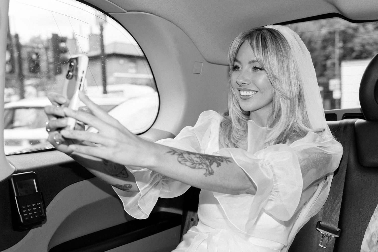 Wedding party members pose playfully in a car during wedding day celebrations.