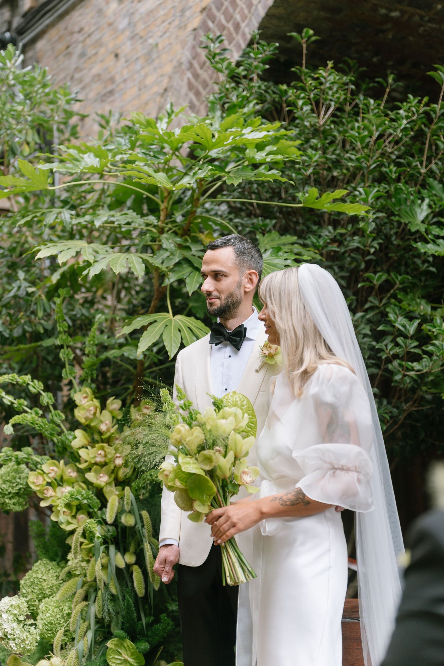 Wedding ceremony scene in an outdoor garden setting with white floral arrangements.