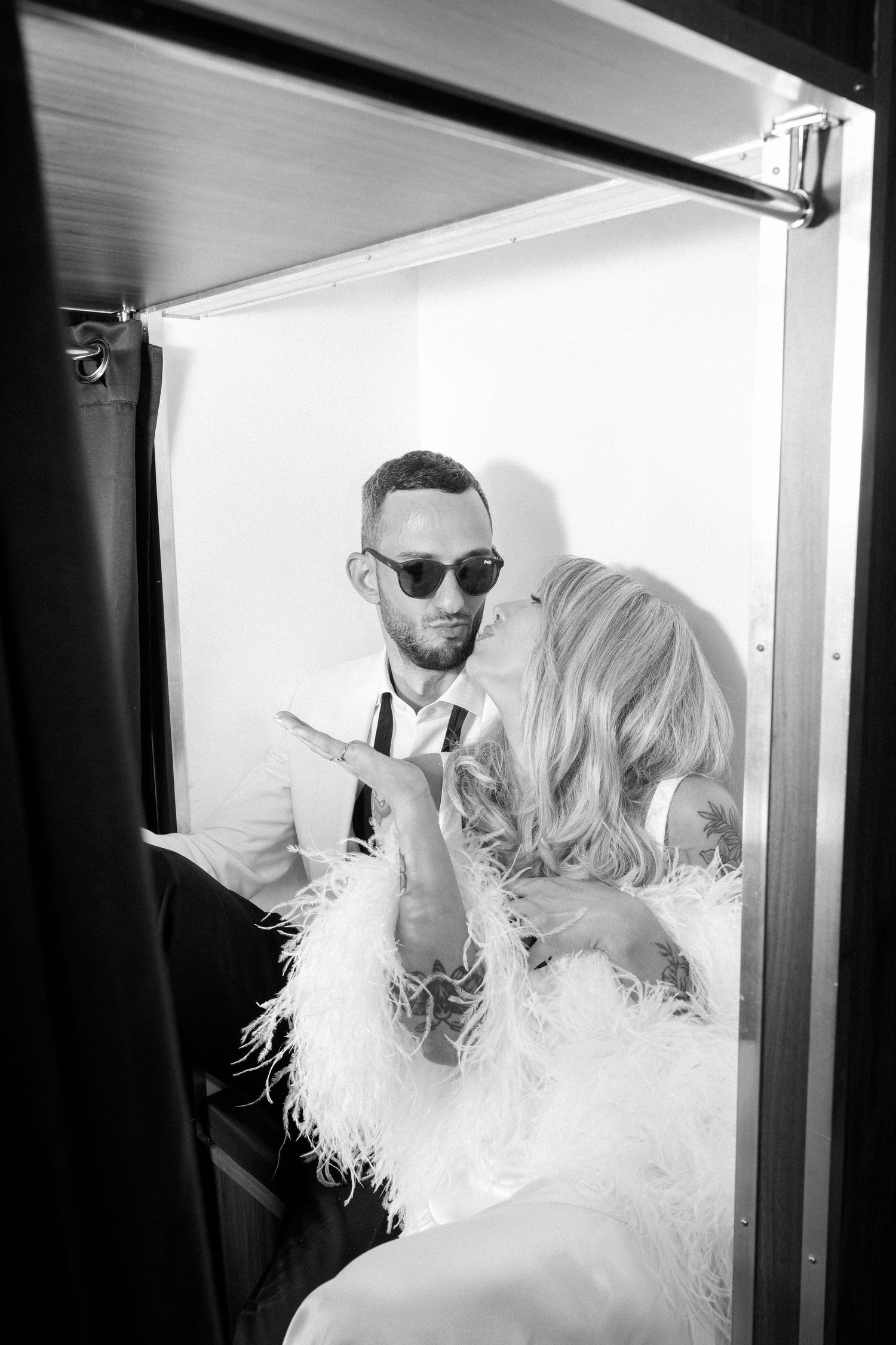 A black and white photo showing a couple getting ready in front of a mirror.