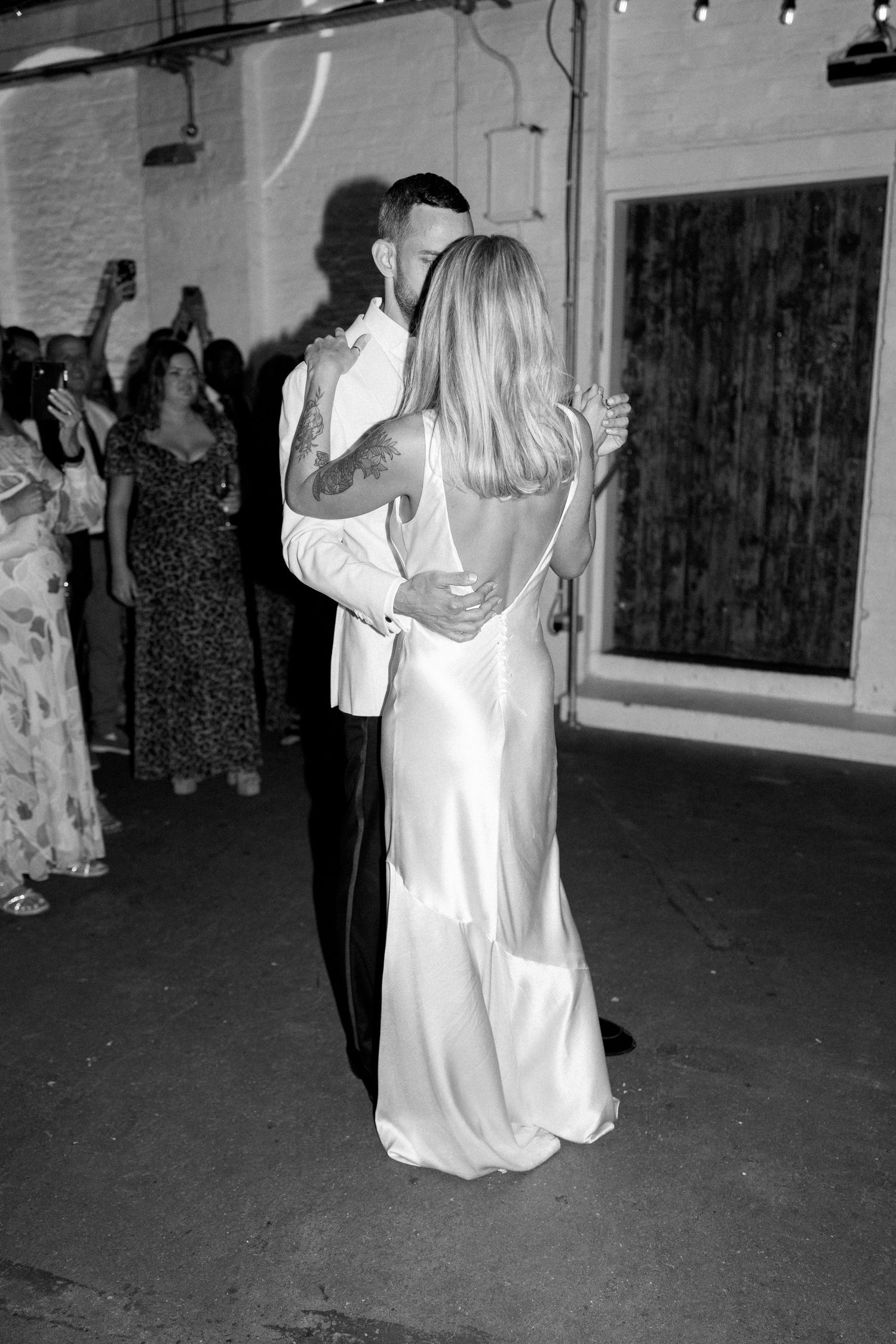 Wedding couples dancing in formal attire under indoor venue lighting.