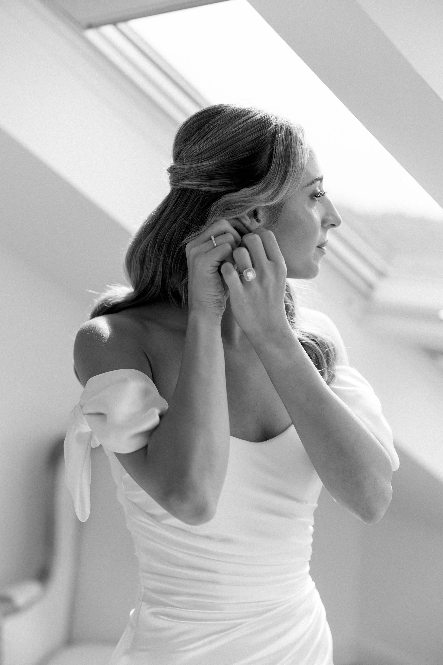 Series showing someone putting on earrings in natural light from skylight window.
