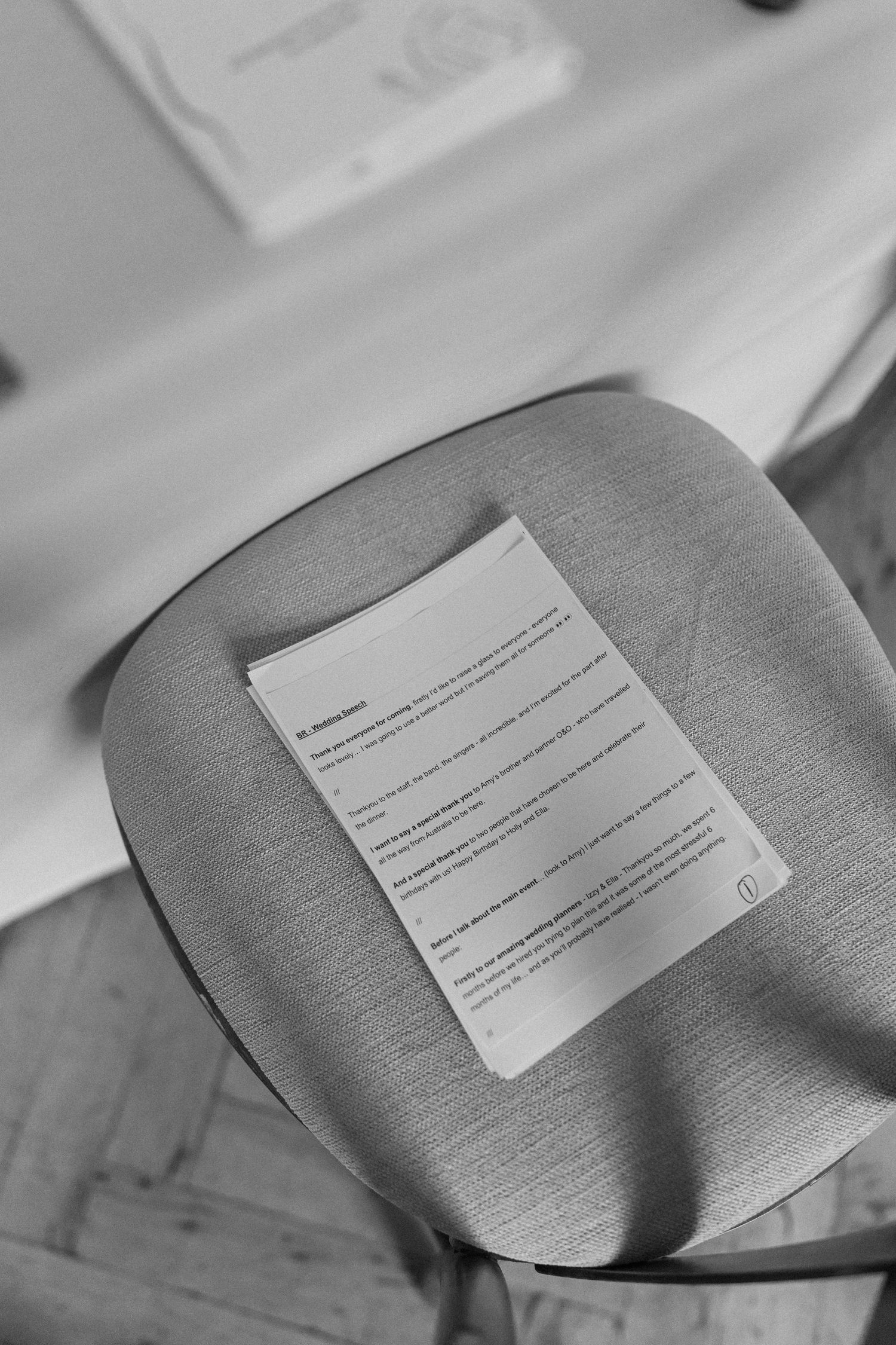 A printed wedding program resting on a gray upholstered chair at an elegant wedding venue.