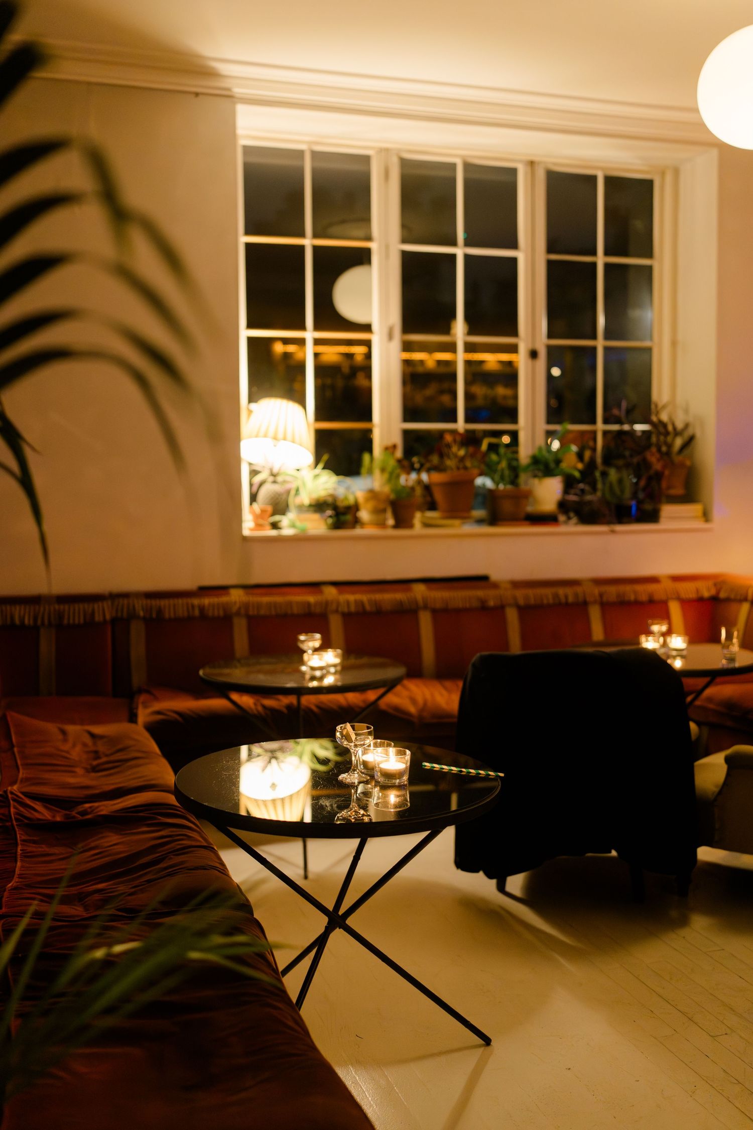 Warmly lit cozy lounge area with candlelight, velvet sofas, and a glass coffee table at a wedding venue.