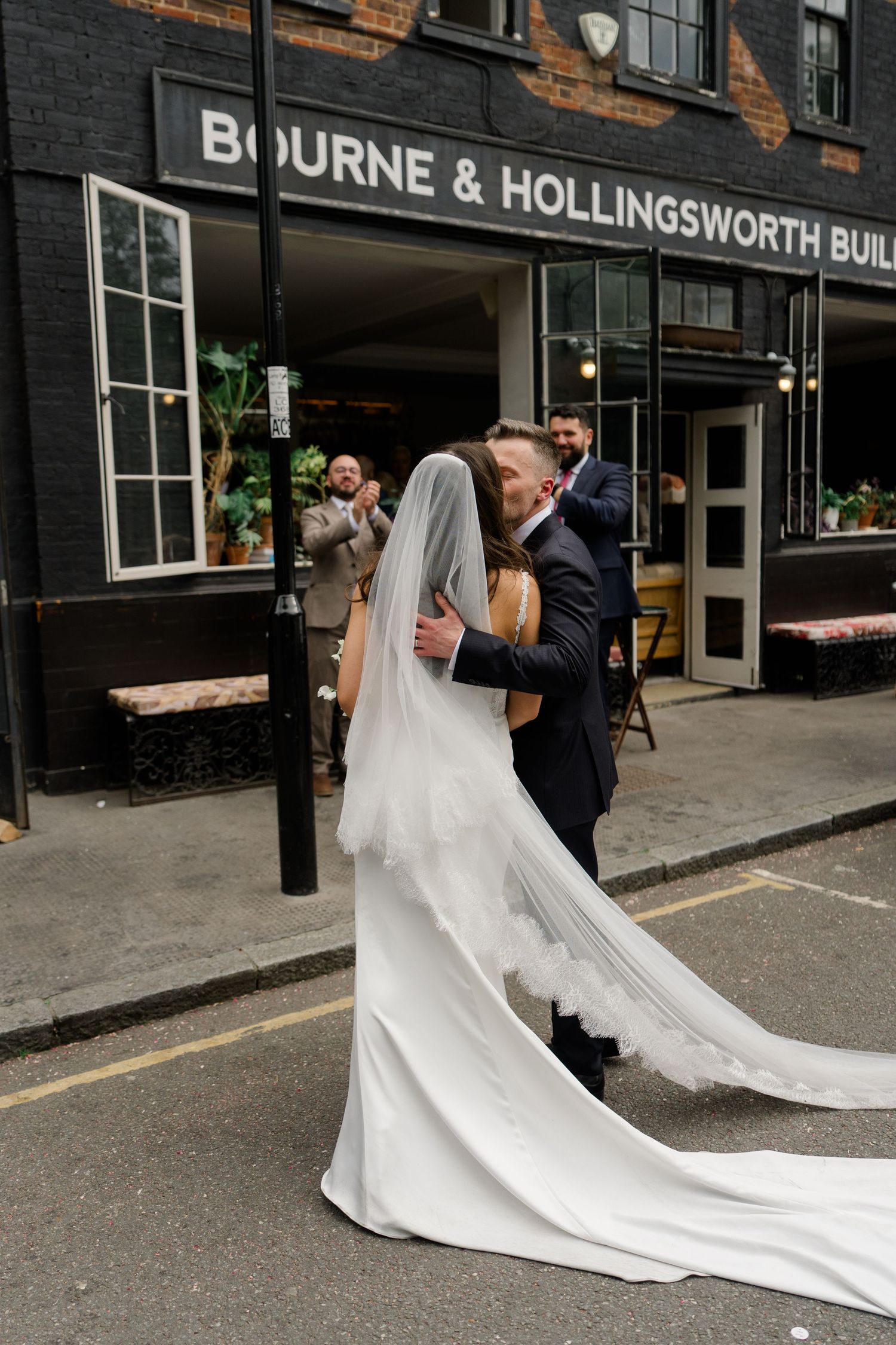 Bride and groom share a romantic embrace outside Bourne and Hollingsworth Buildings.