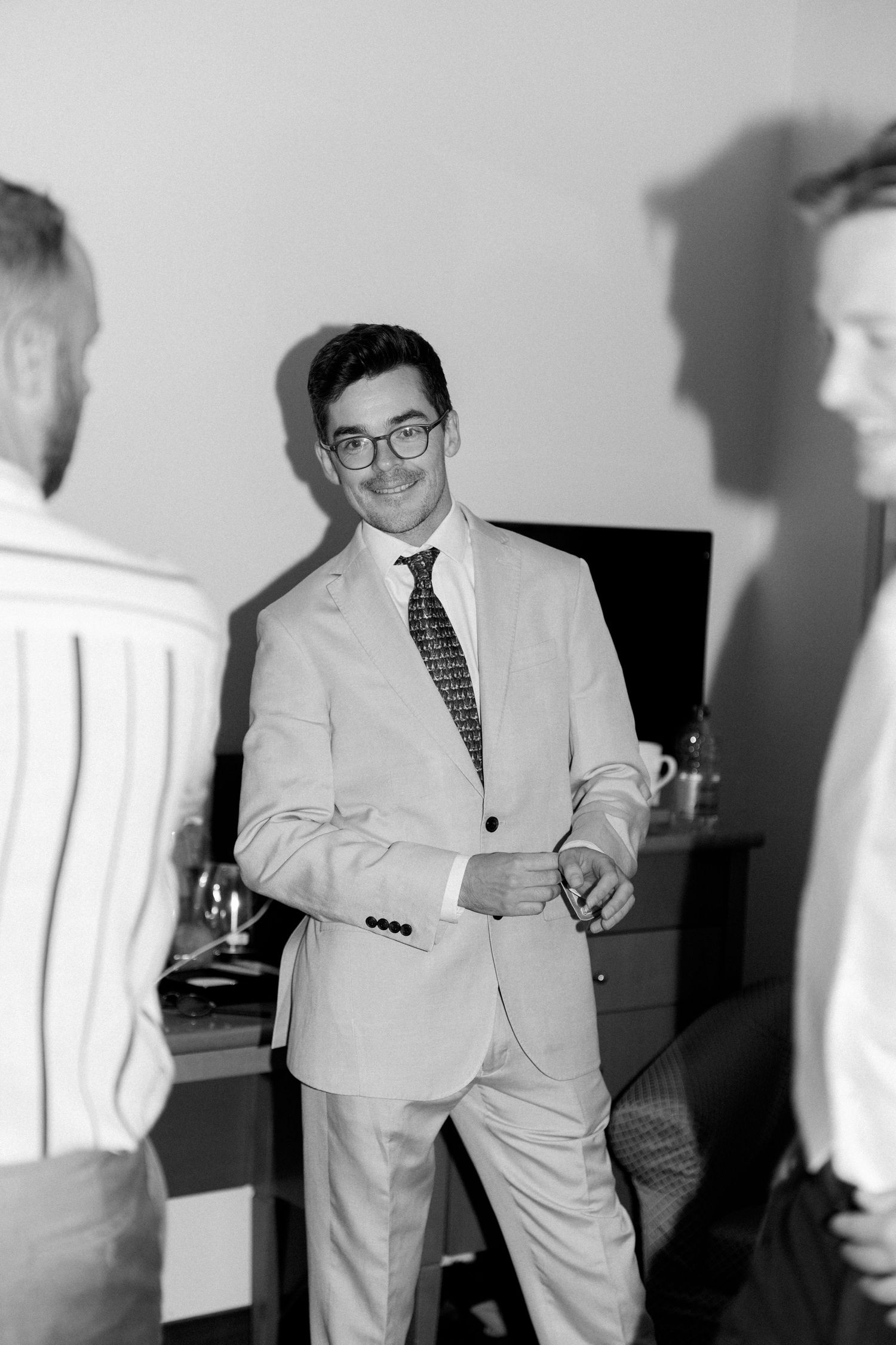 People in light colored suits mingling at formal gathering.