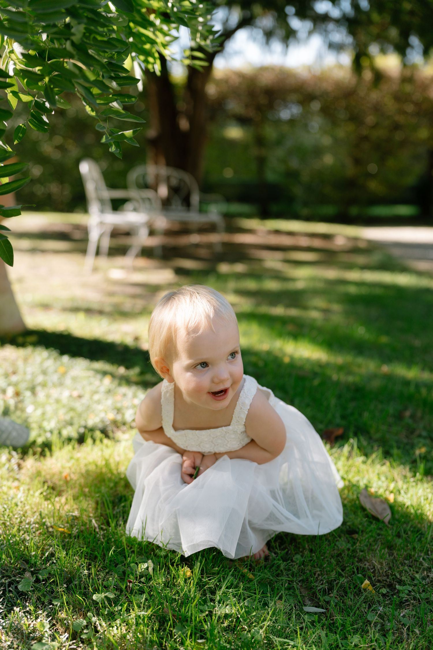 Playful moments captured on grass in a white summer dress.