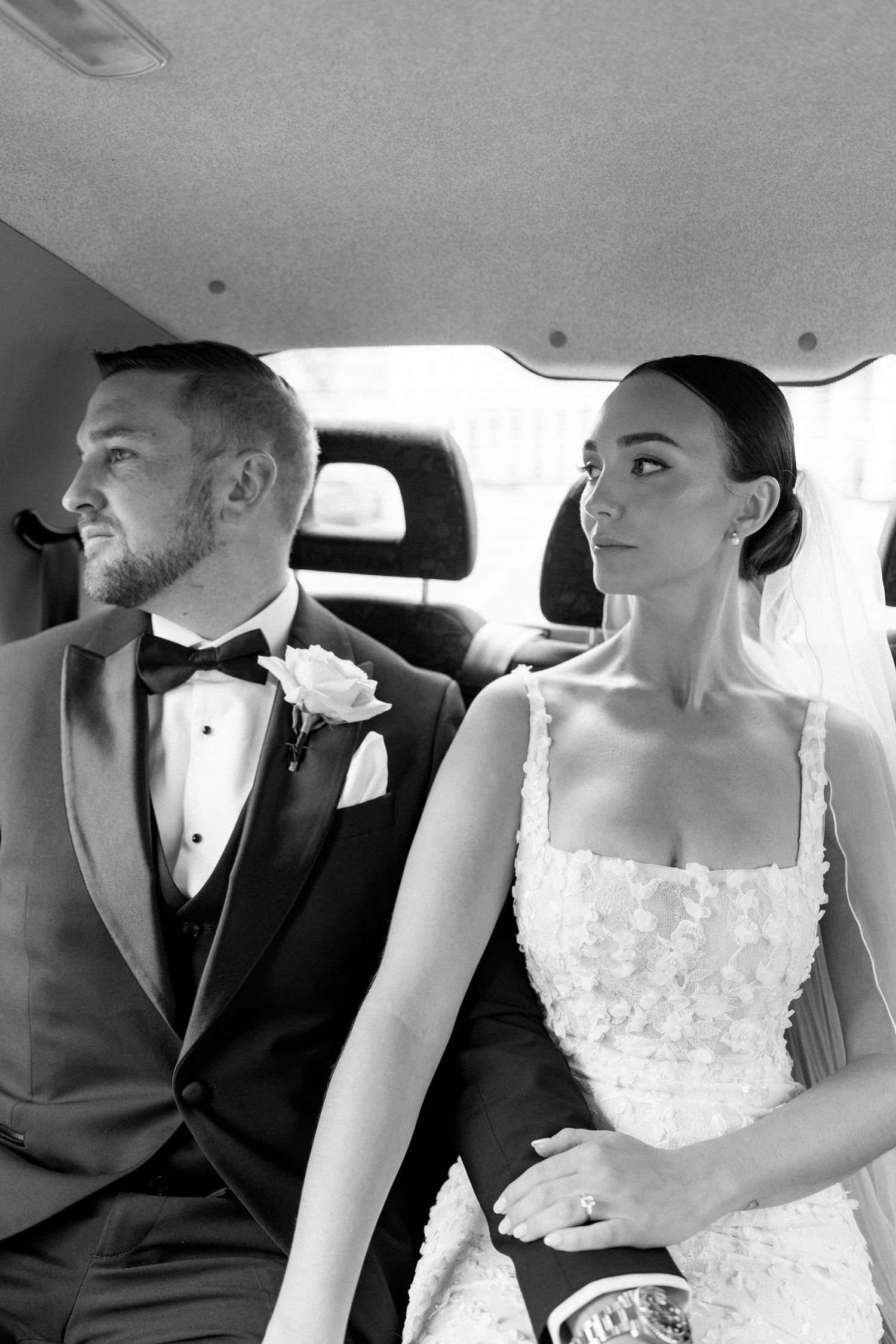 Newlyweds share an intimate moment in the back of a wedding car.
