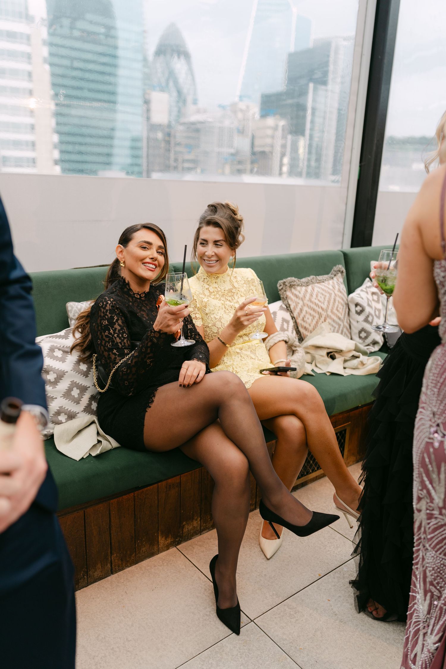 Wedding guests relaxing on a modern couch with city skyline views in the background.