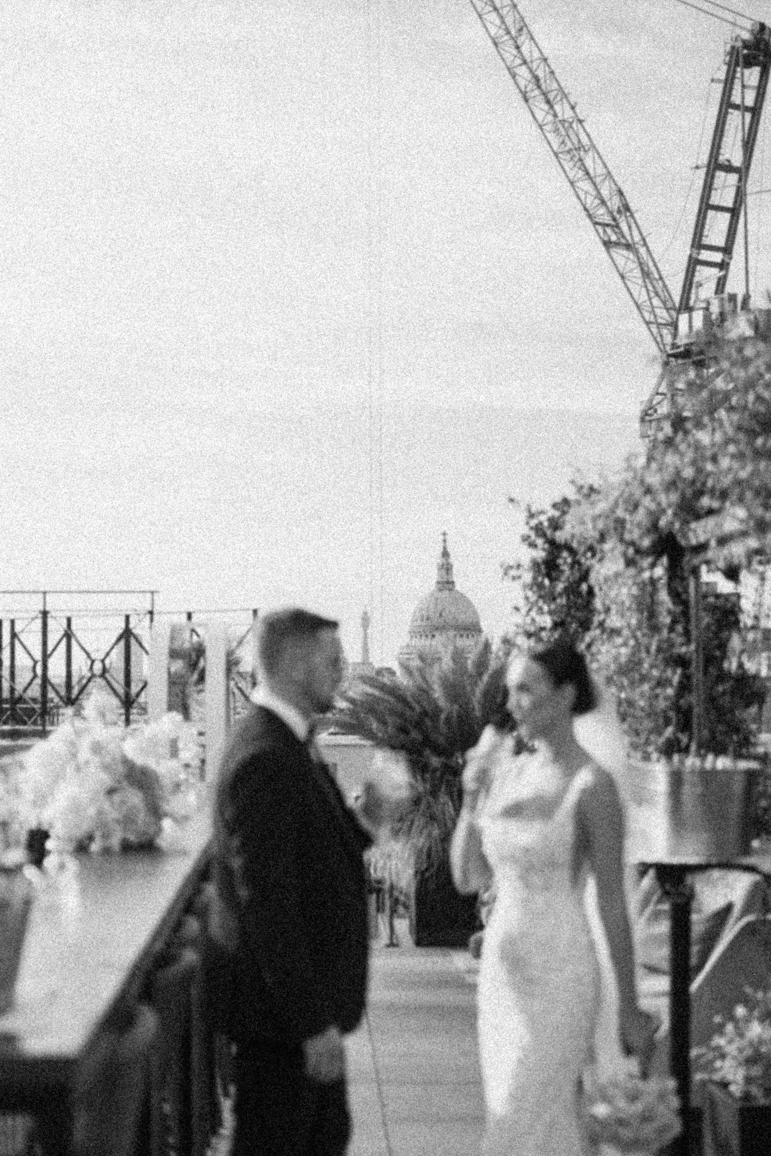 Wedding ceremony taking place on urban rooftop with construction cranes visible.