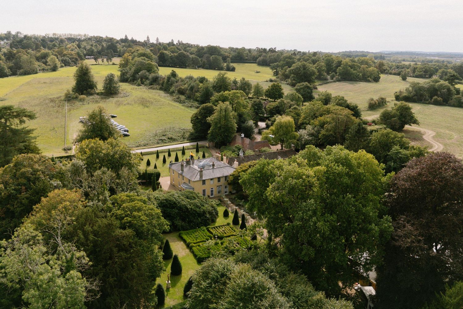 Panoramic view of a grand estate surrounded by rolling countryside and lush greenery.