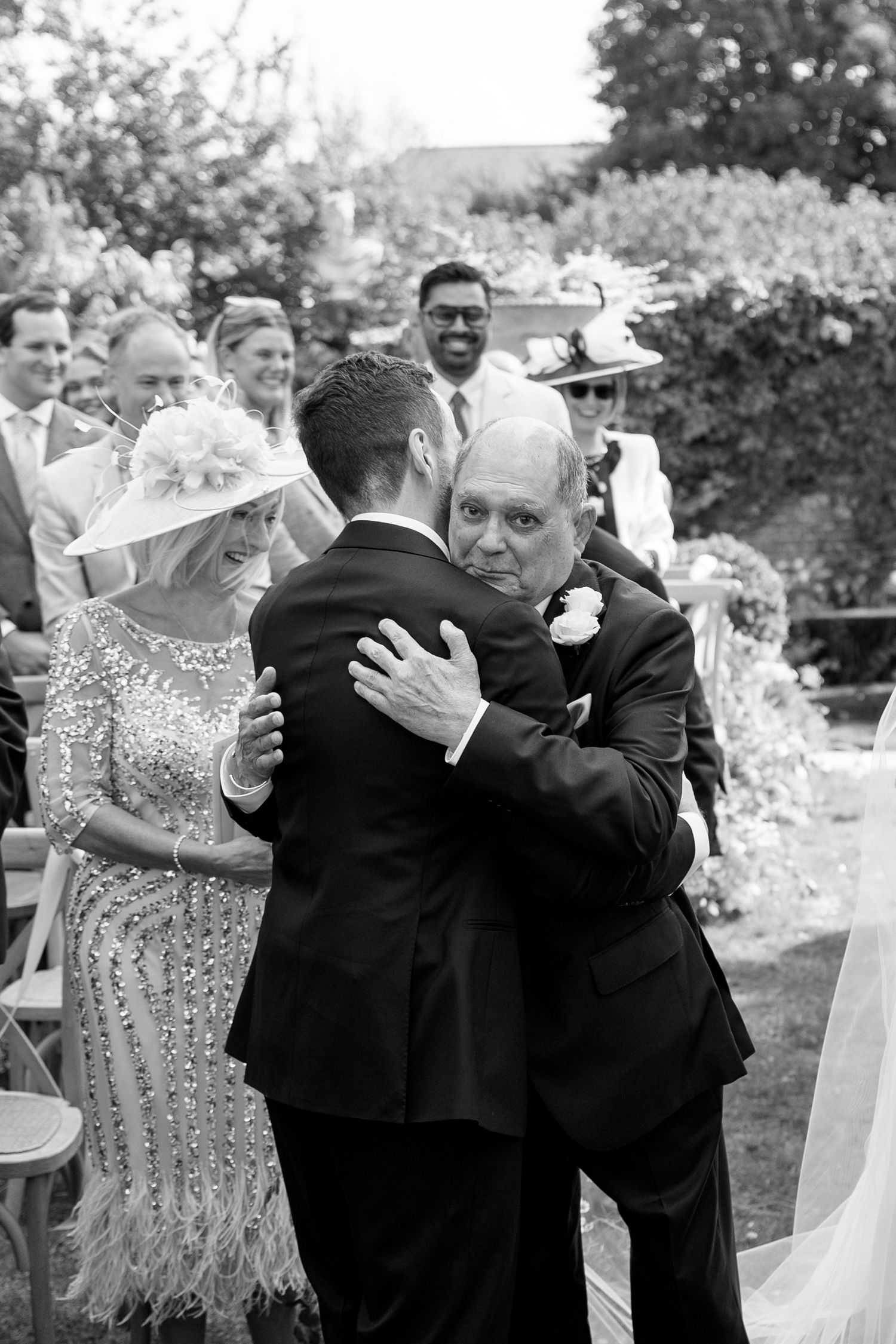 Wedding guests embracing and celebrating during an outdoor garden reception.
