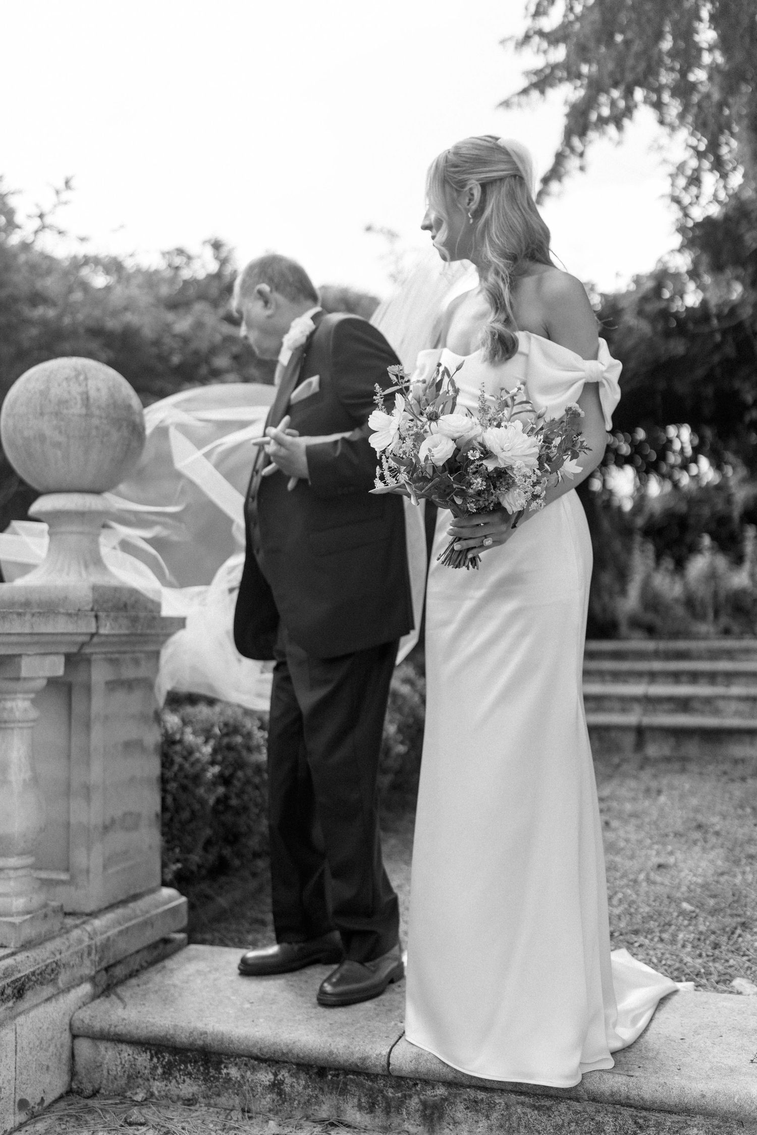 Wedding couple descending stone steps in an outdoor garden setting.