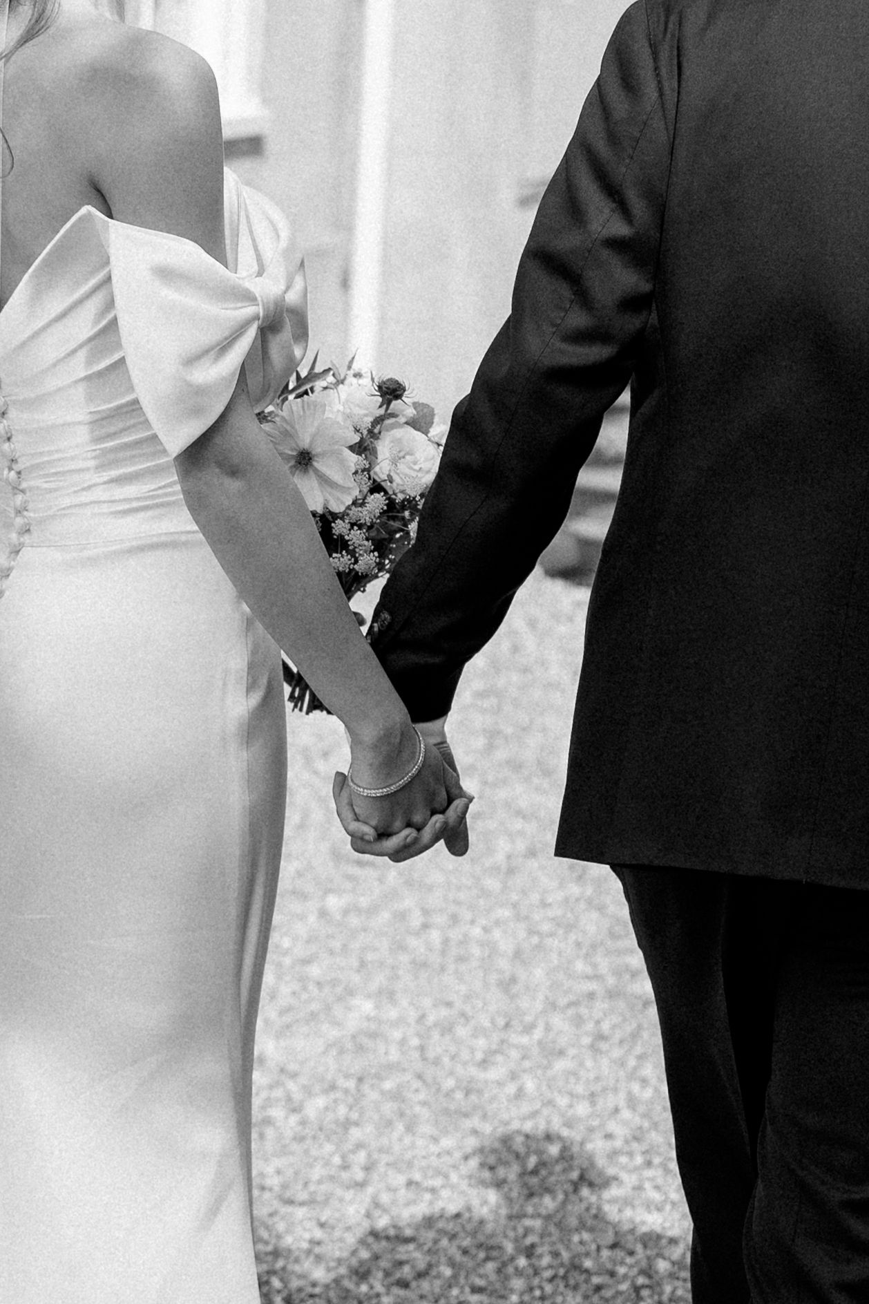 Close-up black and white shots of couple holding hands in formal wedding attire.