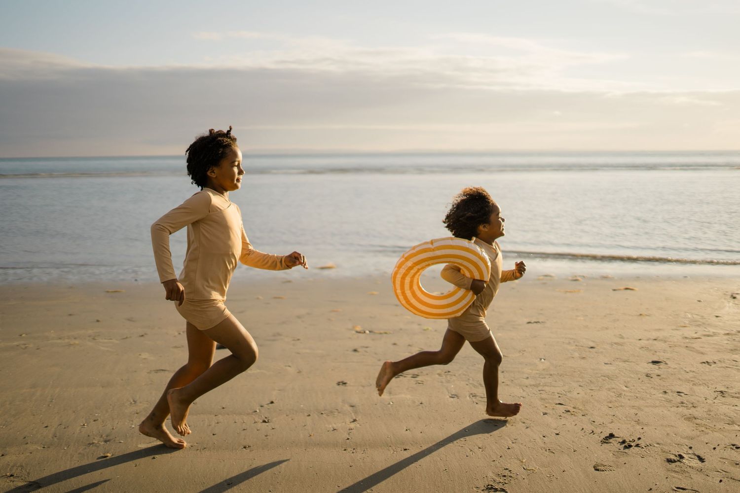Figure running and jumping on empty beach at sunset with frisbee.