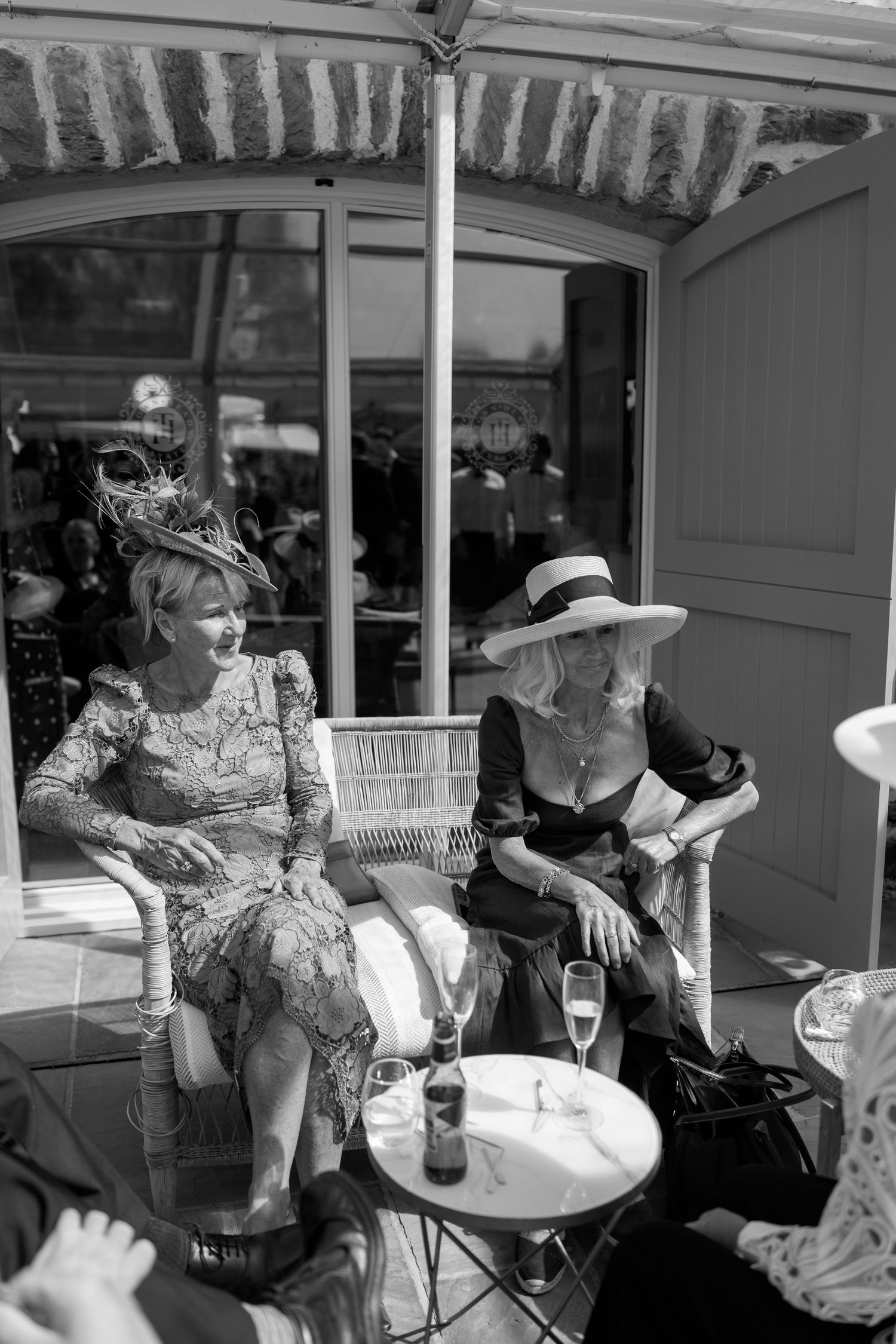 Wedding guests relax at an outdoor covered patio area during a reception.