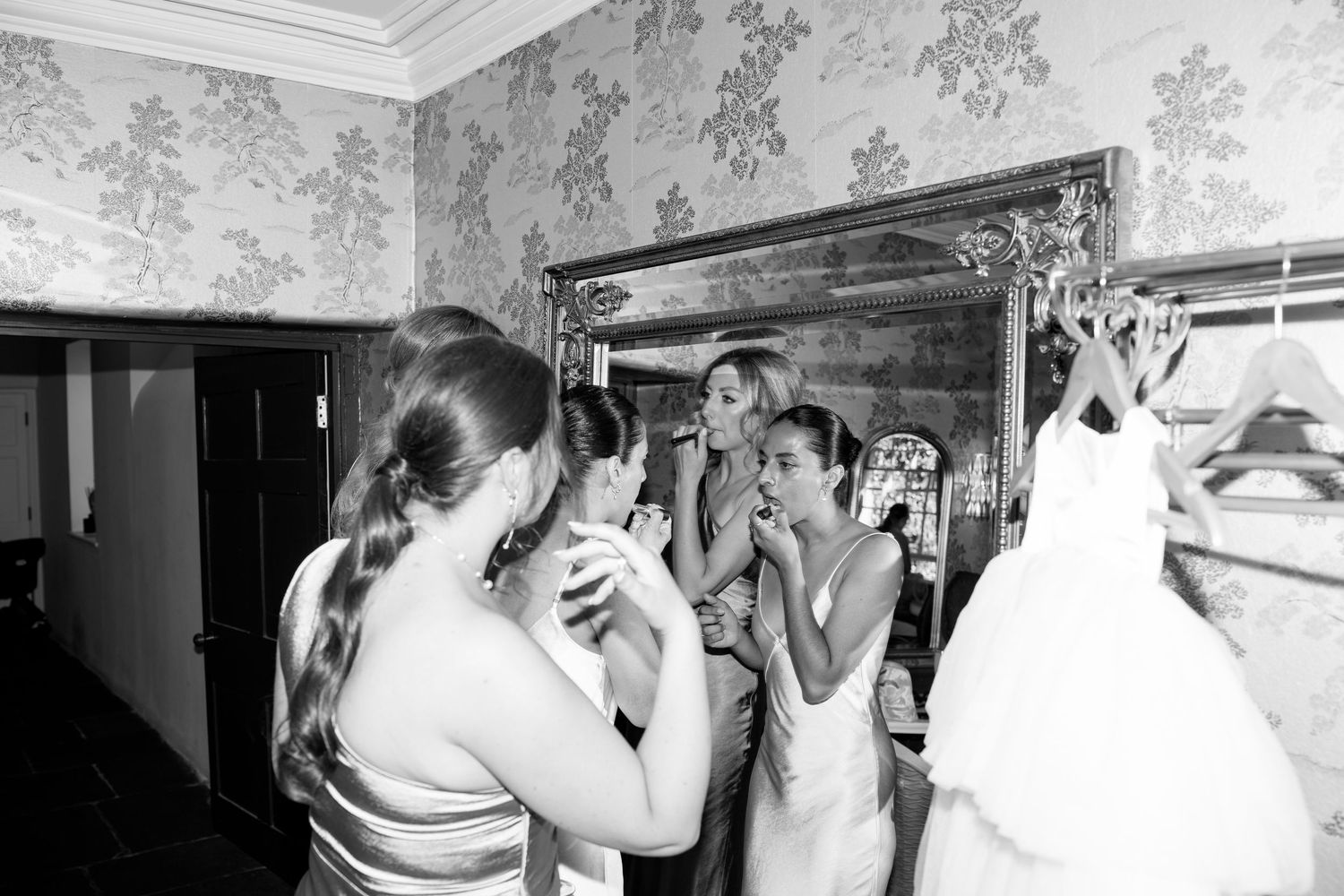 Wedding preparation scene with people getting ready in a room with floral wallpaper.