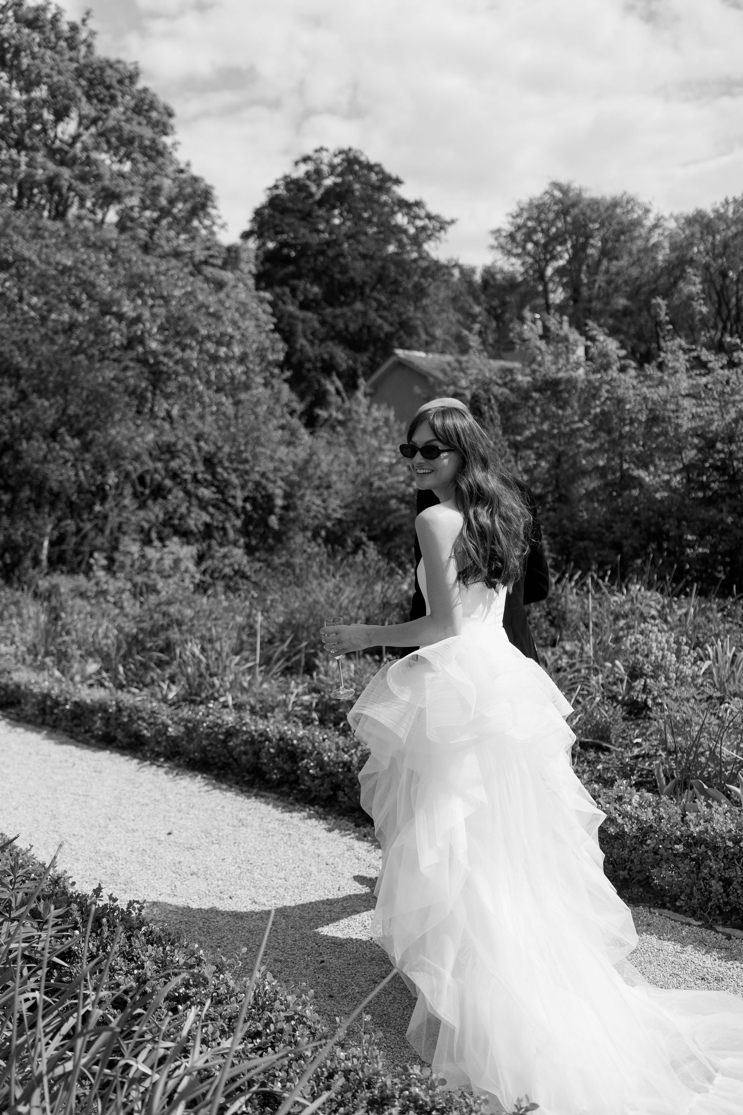 Black and white photos of a bride's flowing dress trailing along a winding garden path.
