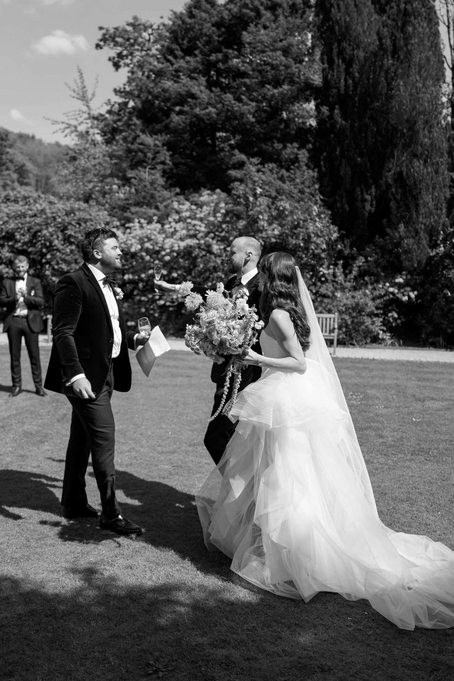 A black and white capture of a wedding ceremony moment in a garden setting.