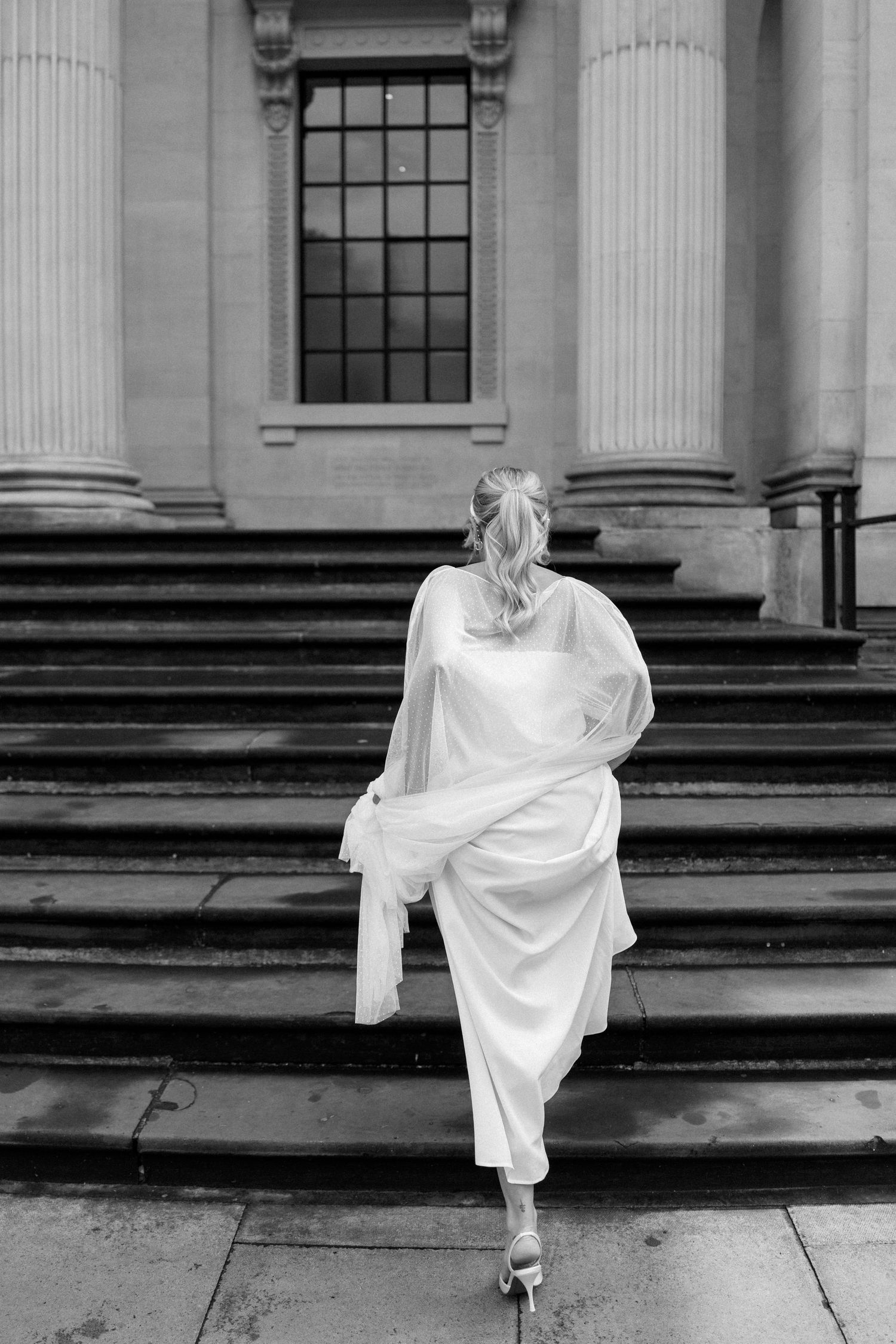 Black and white sequence showing graceful movement up classical stone steps in flowing white fabric.
