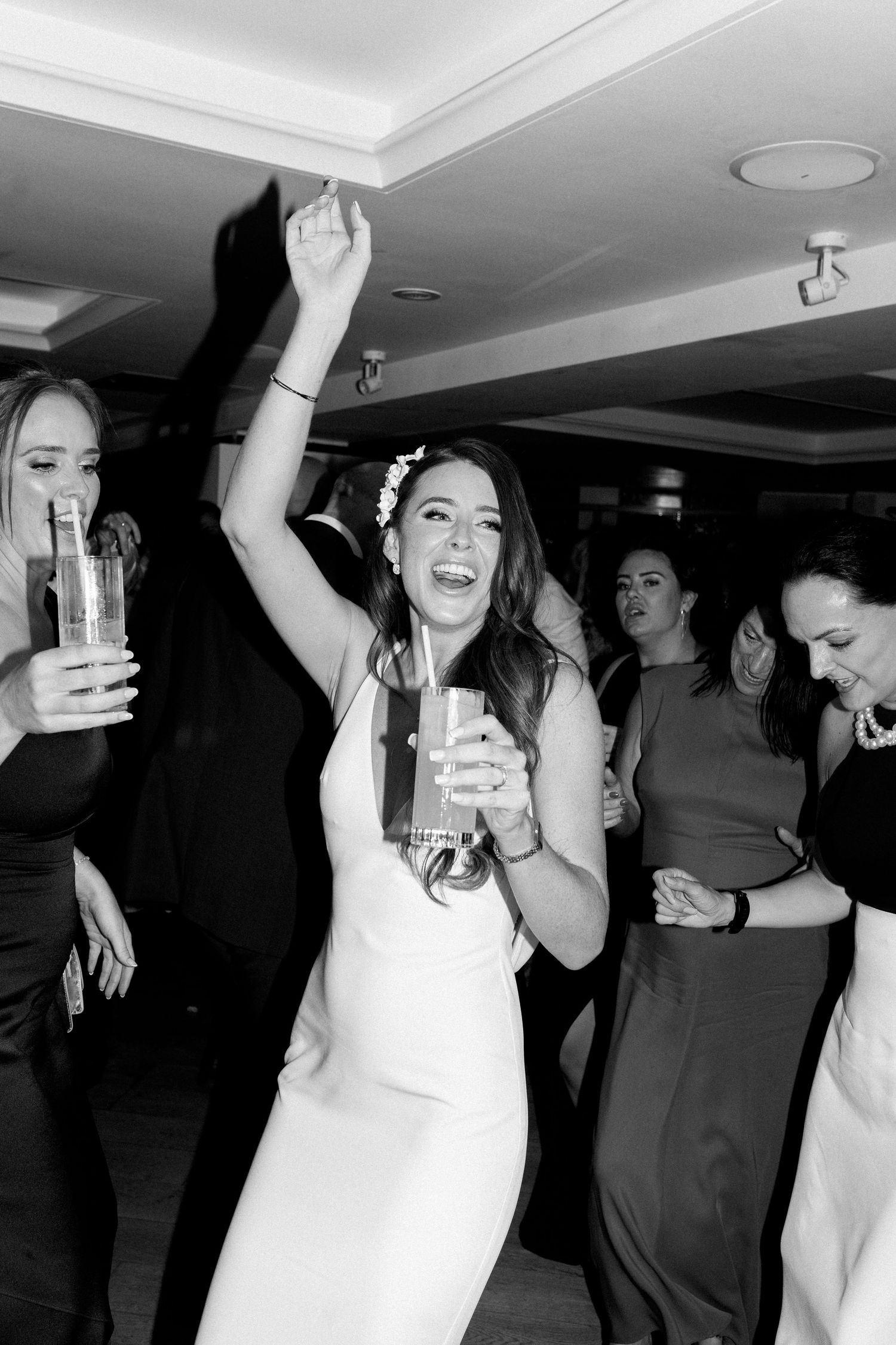 Wedding party dancing and celebrating in dimly lit reception venue.