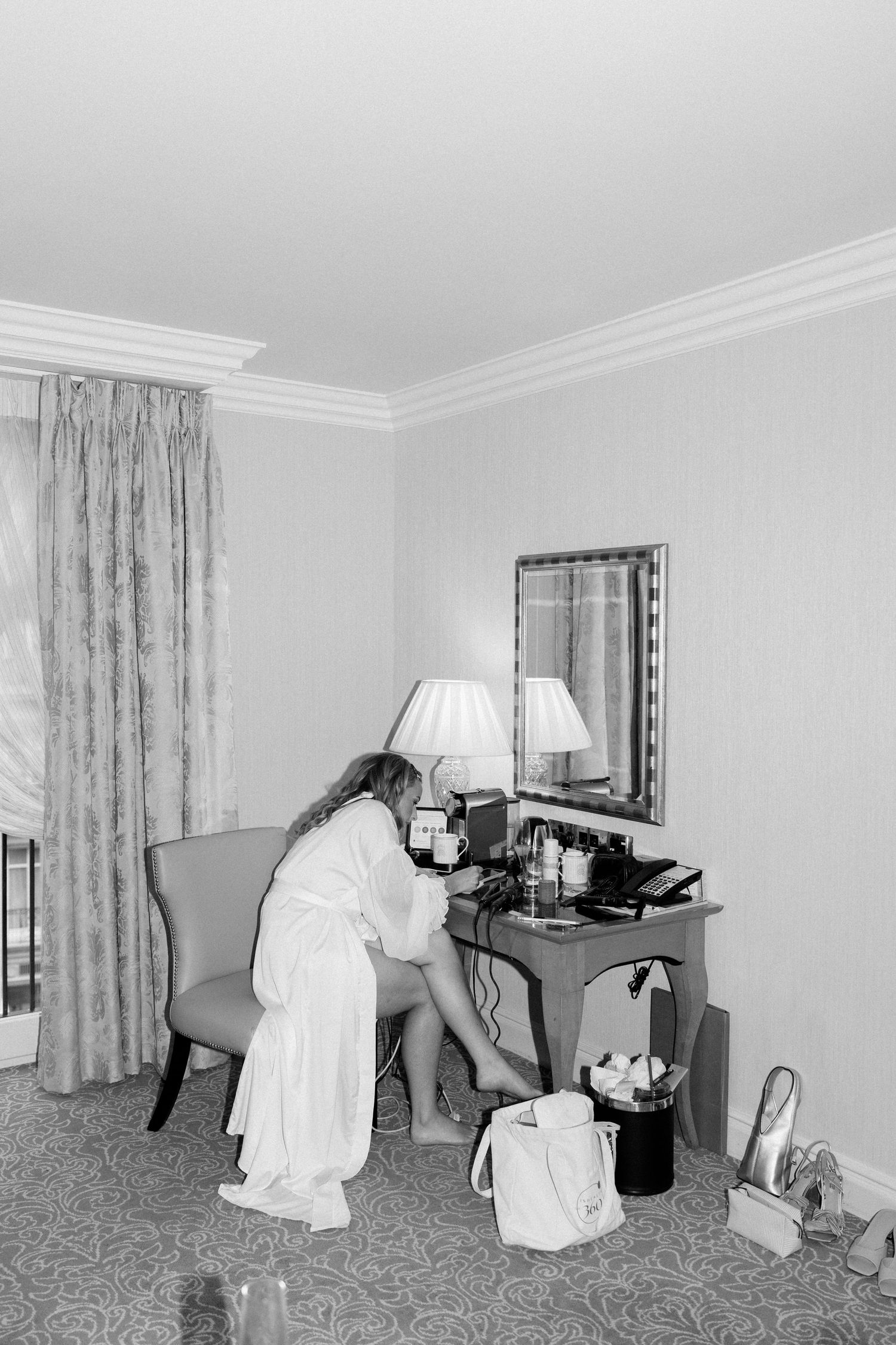 Series of black and white photos showing someone in white clothing leaning over a desk in a hotel room.