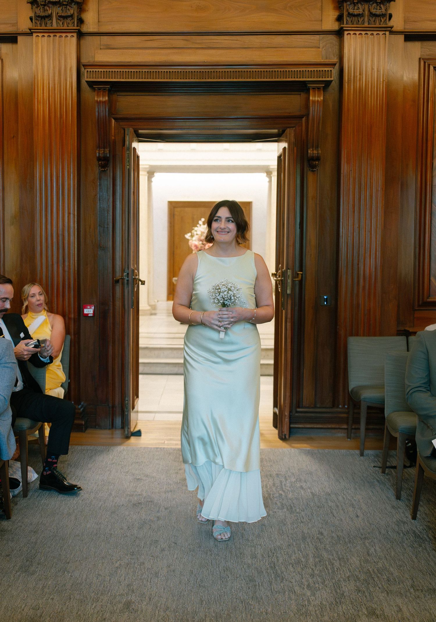 Wedding ceremony in an elegant wood-paneled room with large windows and carpeted floor.