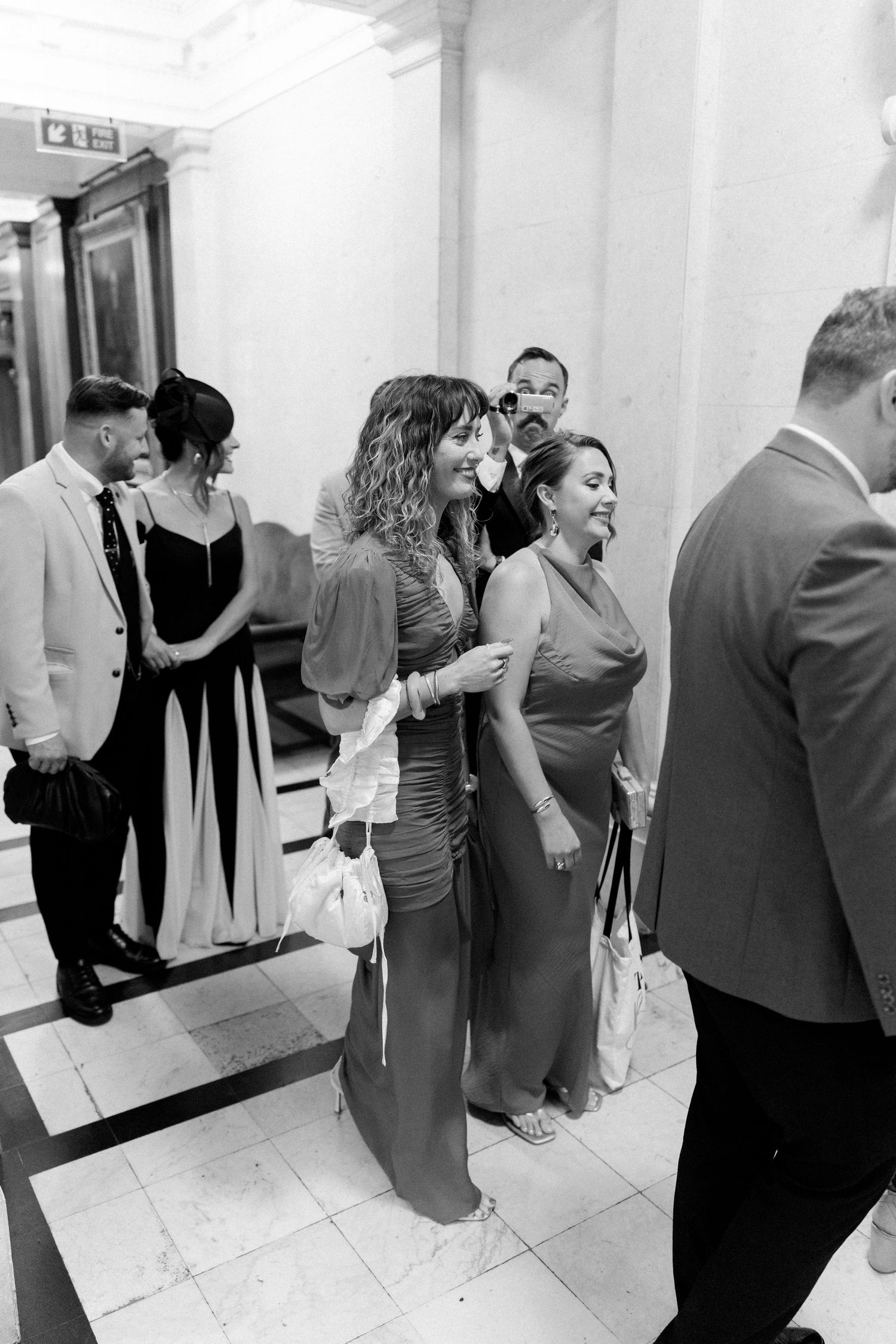 Wedding guests gathered in an elegant hallway sharing candid moments together.