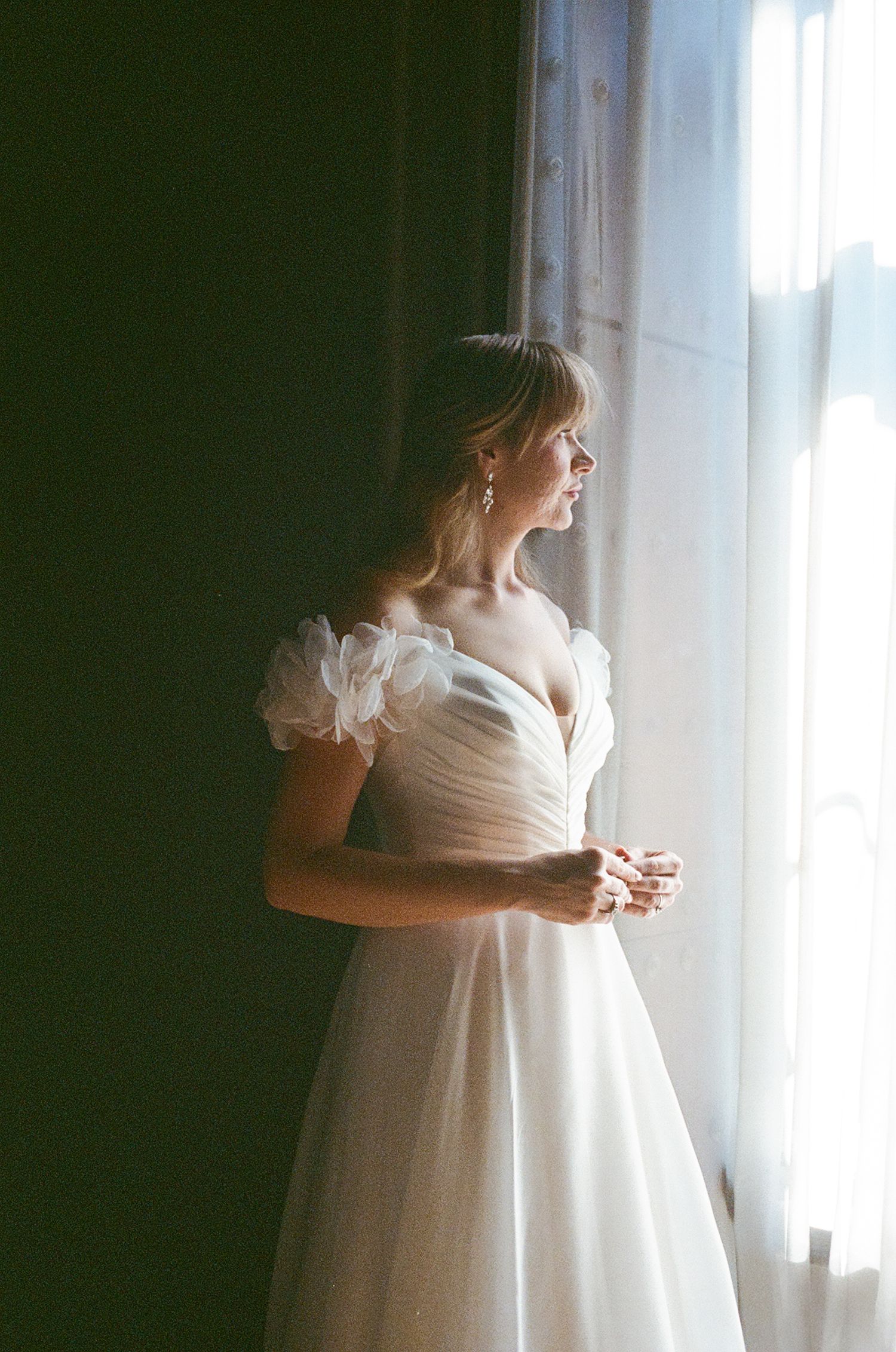 Ethereal bridal portraits by a window with soft natural lighting and flowing white fabric.